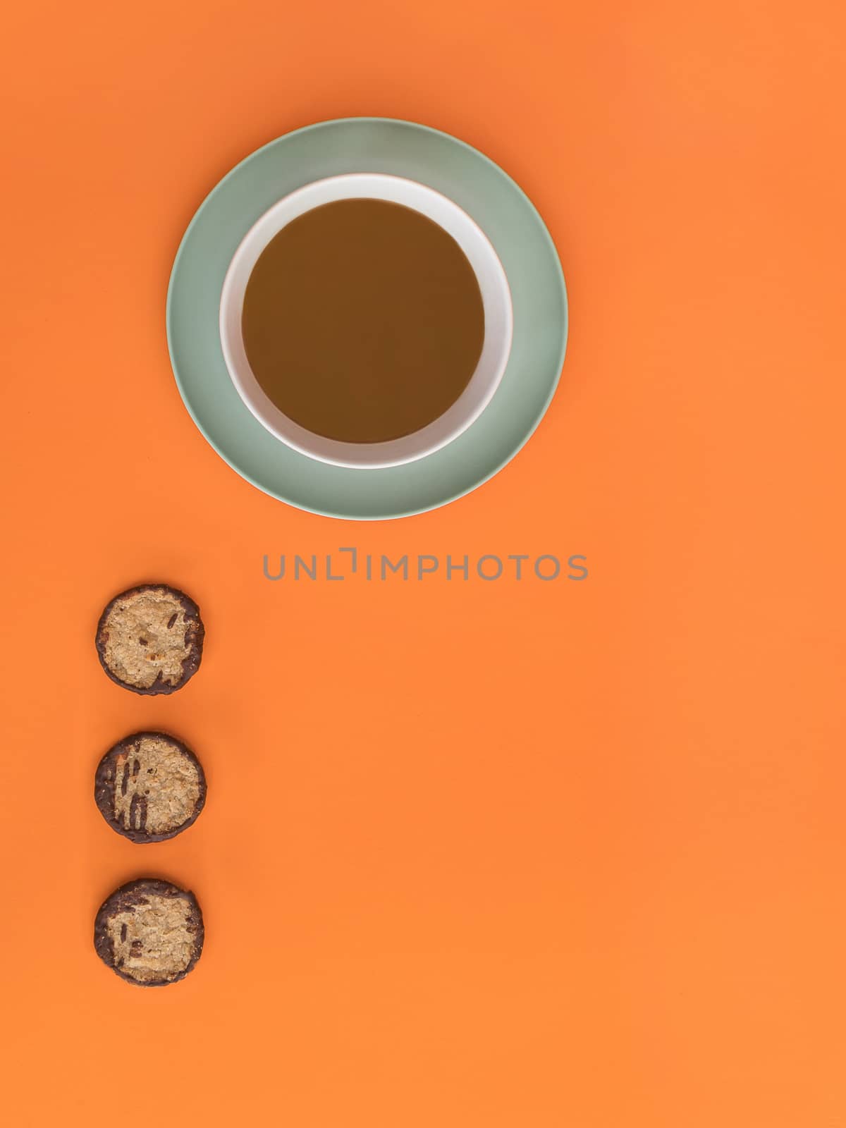 Chocolate bowl on a green light plate and three cookies. Orange background. Copy space. Top view.