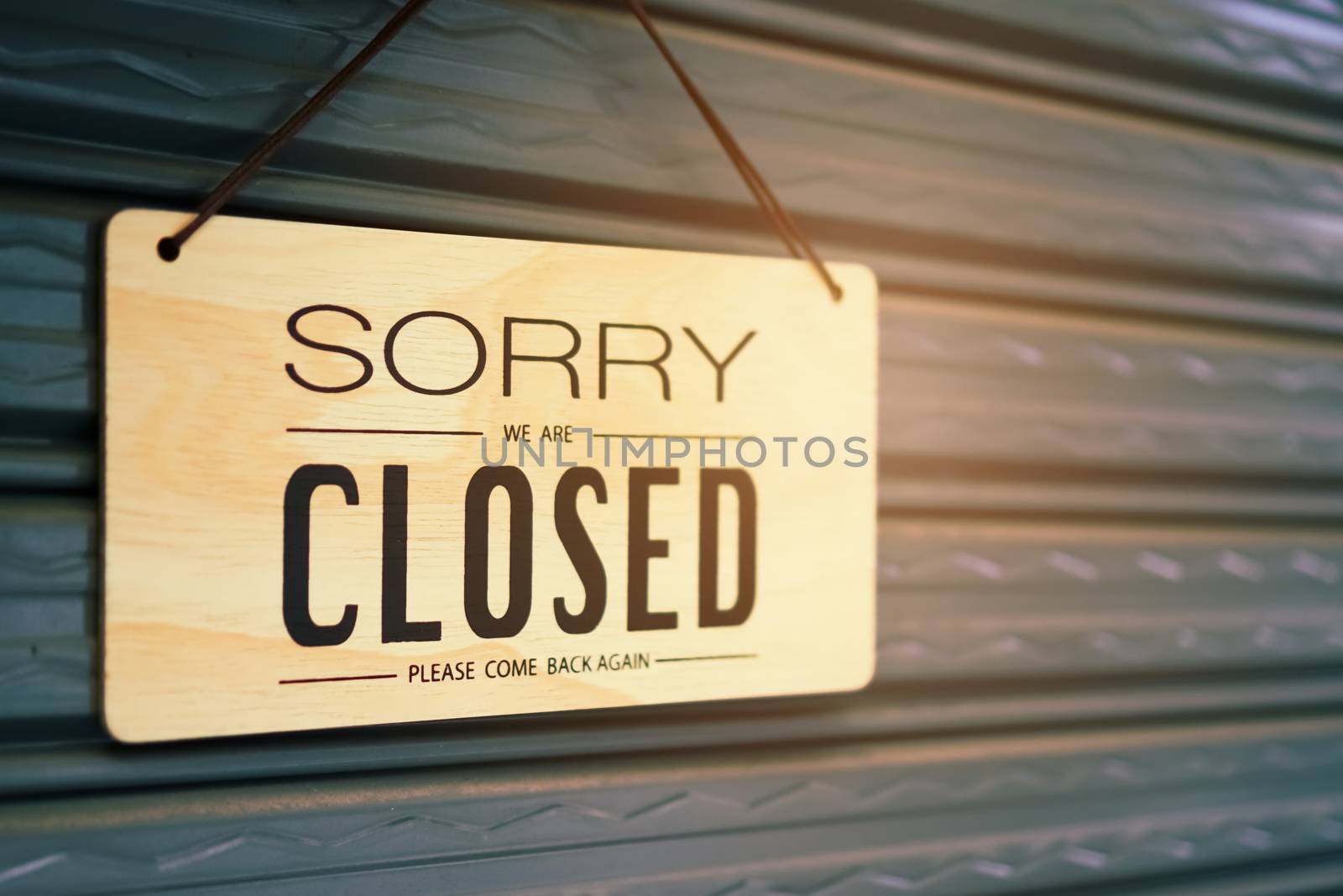 A Sign board of sorry we are closed hang on door of business shop with nature green background