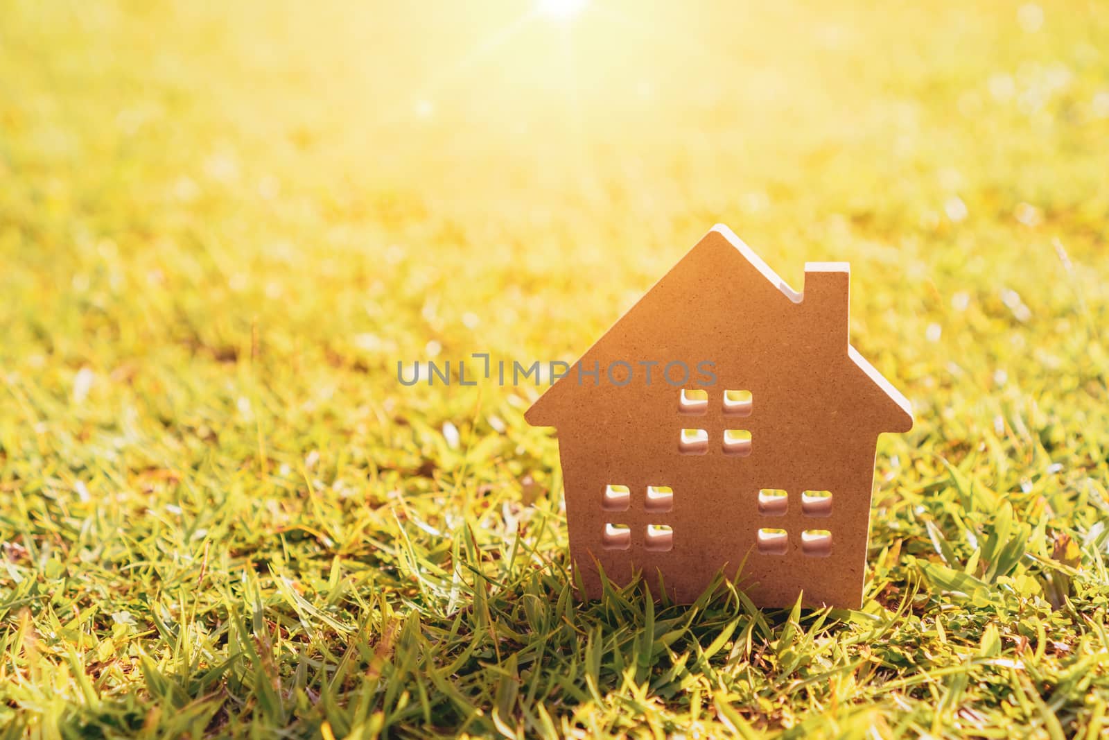 Closed up tiny home model on green grass with sunlight background.