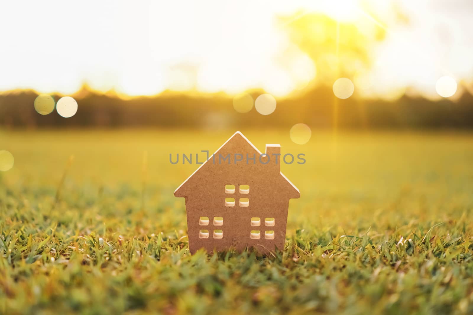 Closed up tiny home model on green grass with sunlight background.