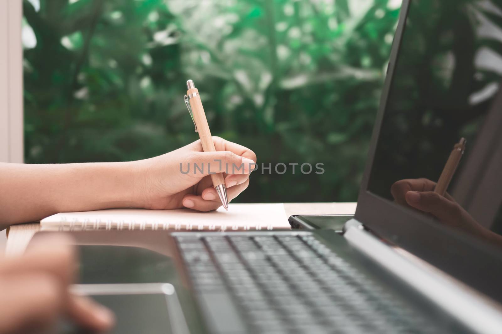 Woman hand write down in white memo notebook for take a note not to forget, to do list or plan for work in future on work desk.
