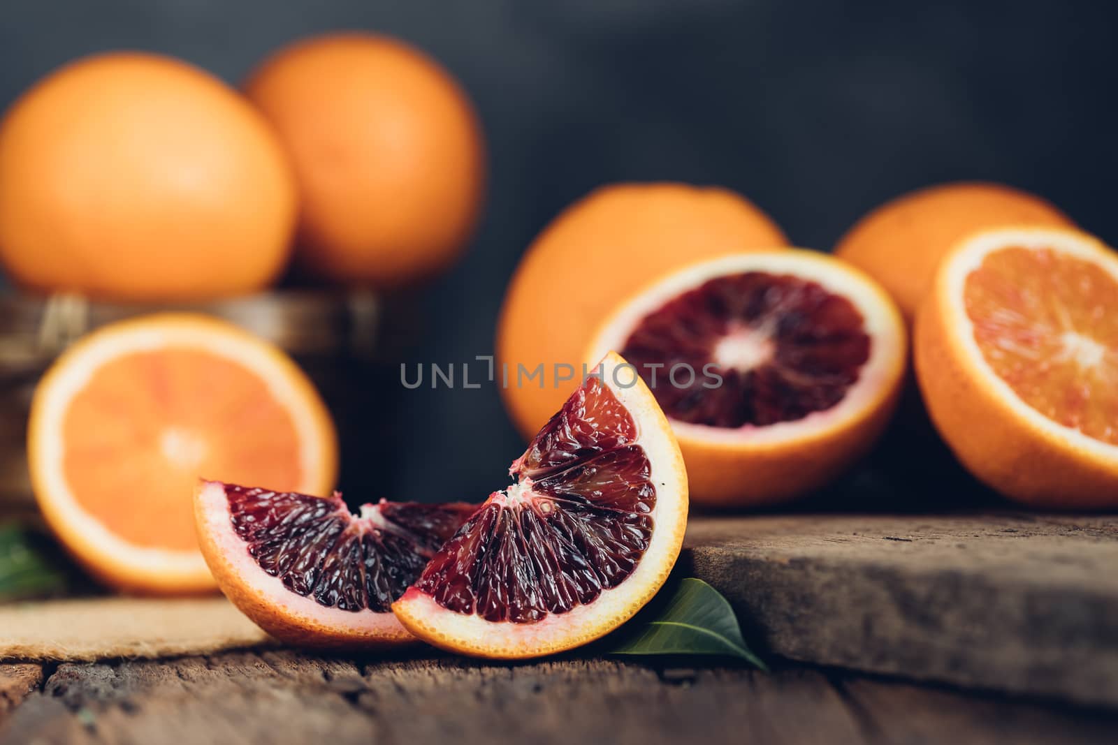 Sliced Sicilian Blood oranges fruits over old dark wooden background. Top view.