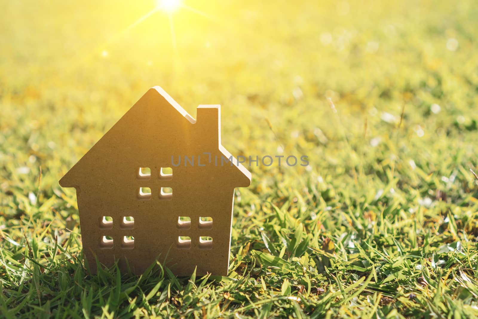 Closed up tiny home model on green grass with sunlight background.