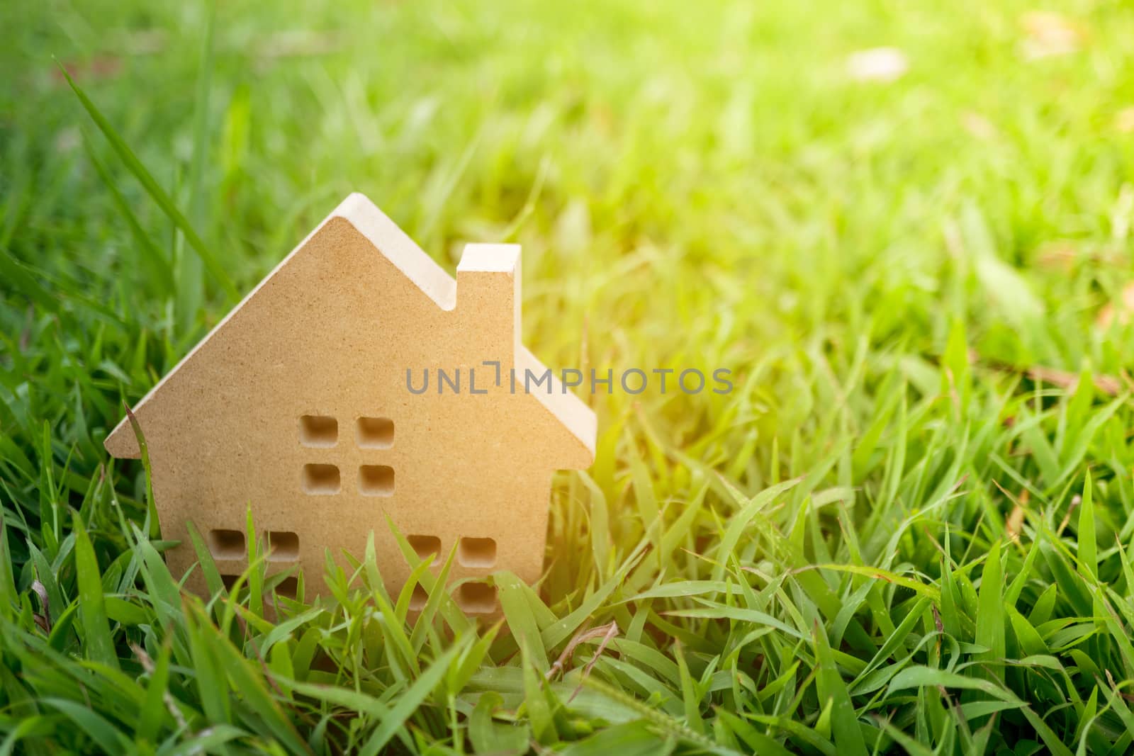 Closed up tiny home model on green grass with sunlight background.