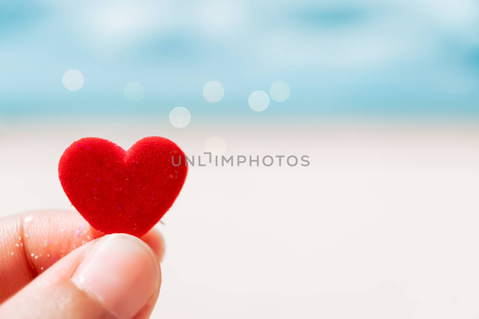 Hand hold little heart meaning feel love with summer beach with blue sky background.