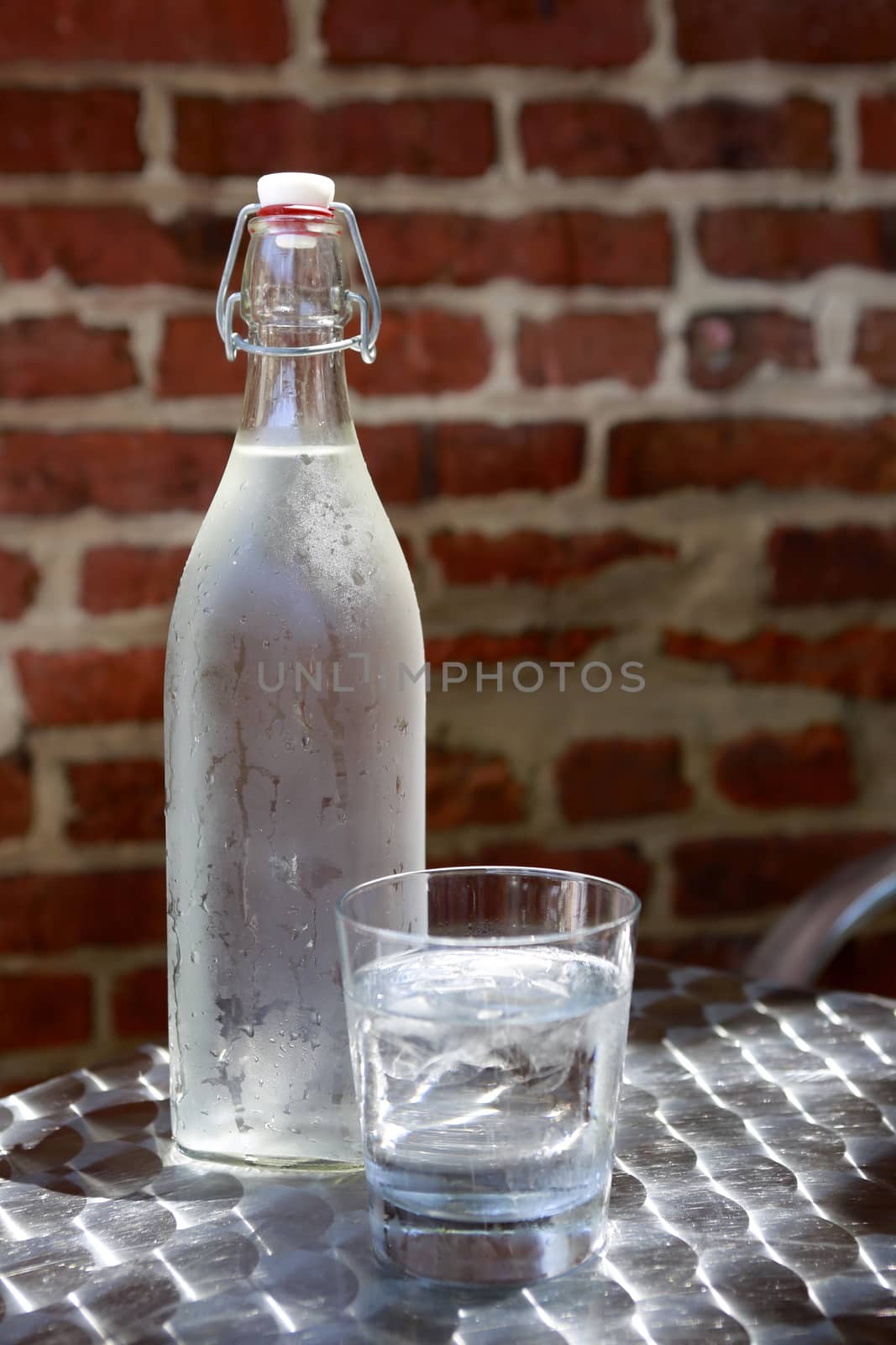 Bottle of cold water in hot summer day on brick wall background