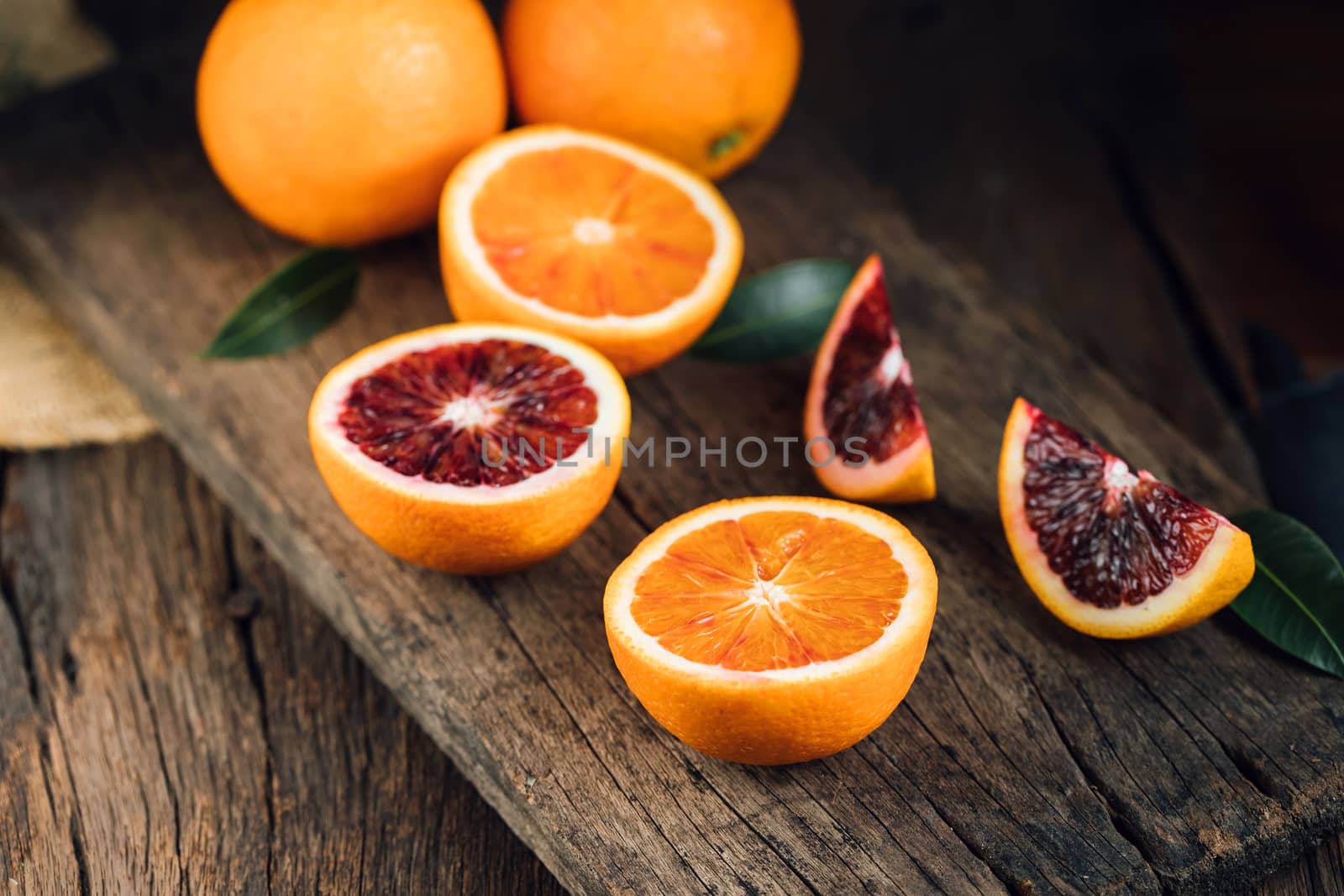 Sliced Sicilian Blood oranges fruits over old dark wooden background. Top view.