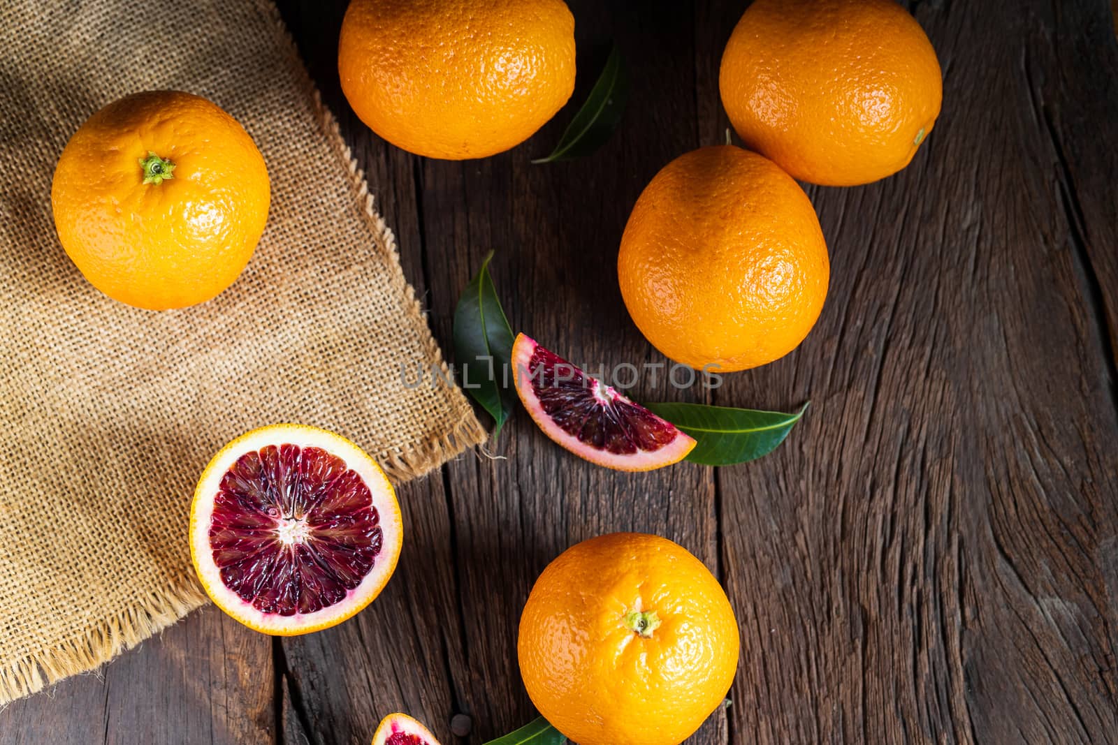 Sliced Sicilian Blood oranges fruits over old dark wooden background. Top view.