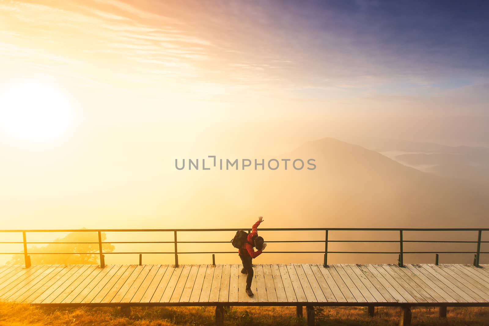 Silhouette of man hold up hands on the peak of mountain,success concept