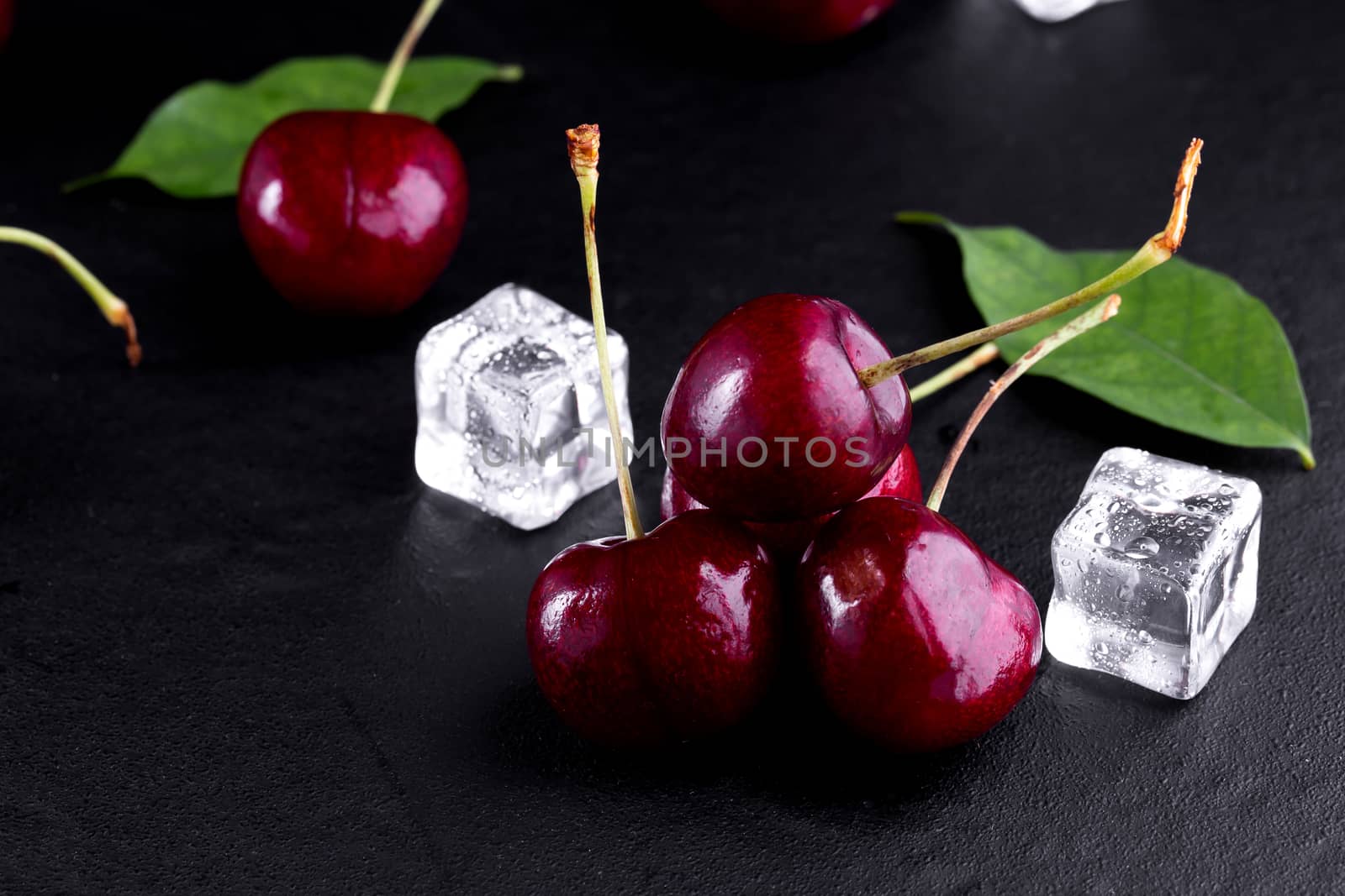 Close up of pile of ripe cherries with stalks and leaves. by freedomnaruk