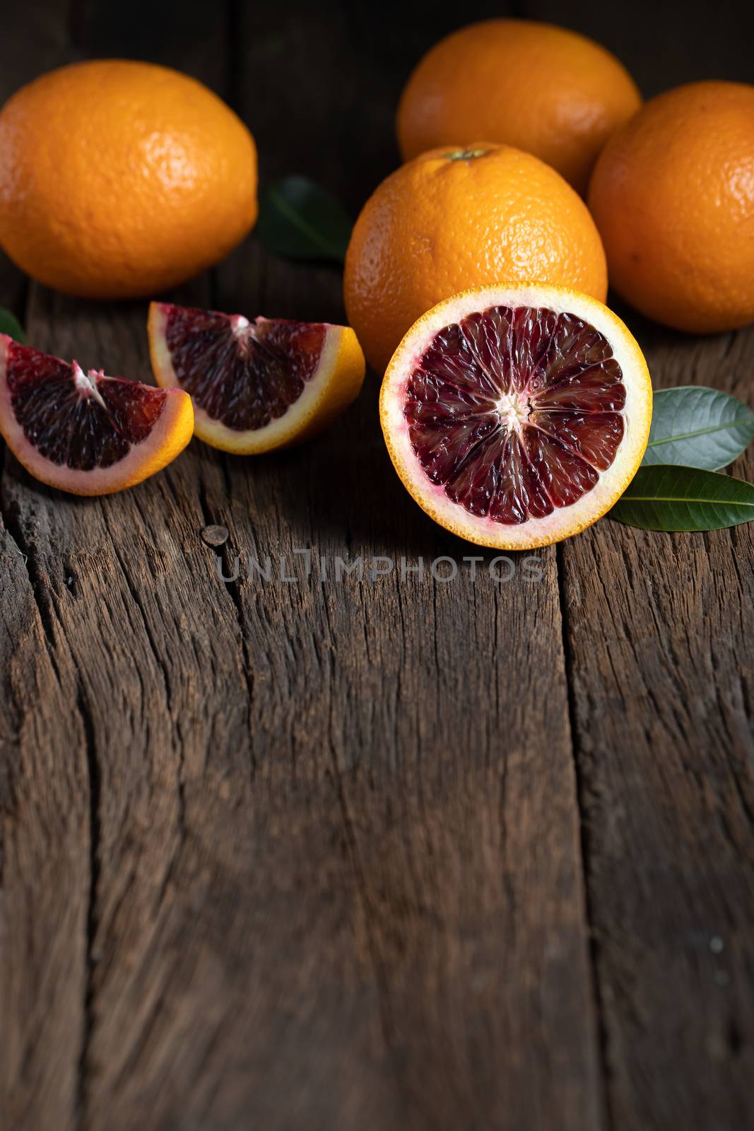 Sliced Sicilian Blood oranges fruits over old dark wooden background. Top view.