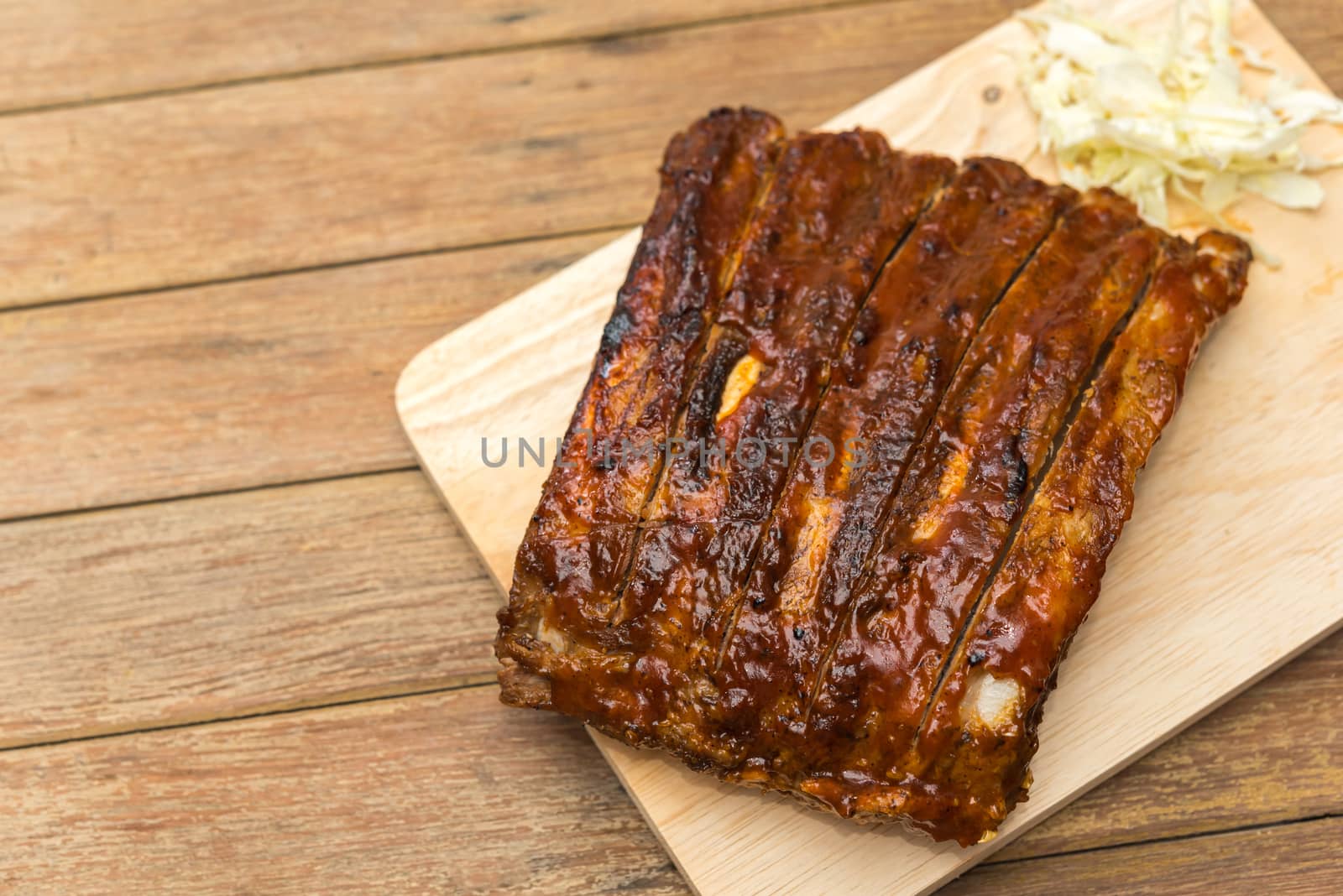 Roasted Pork Spare Ribs Barbecue or Pork Ribs with BBQ Sauce on wooden cutting board in kitchen at Thai street food market or restaurant