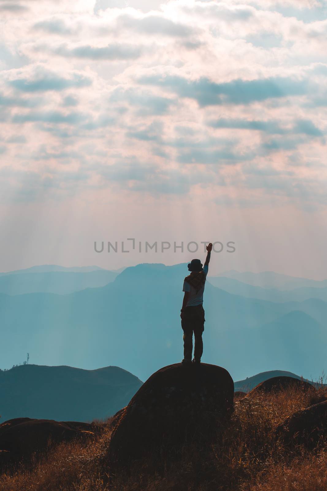 Silhouette of man hold up hands on the peak of mountain,success concept