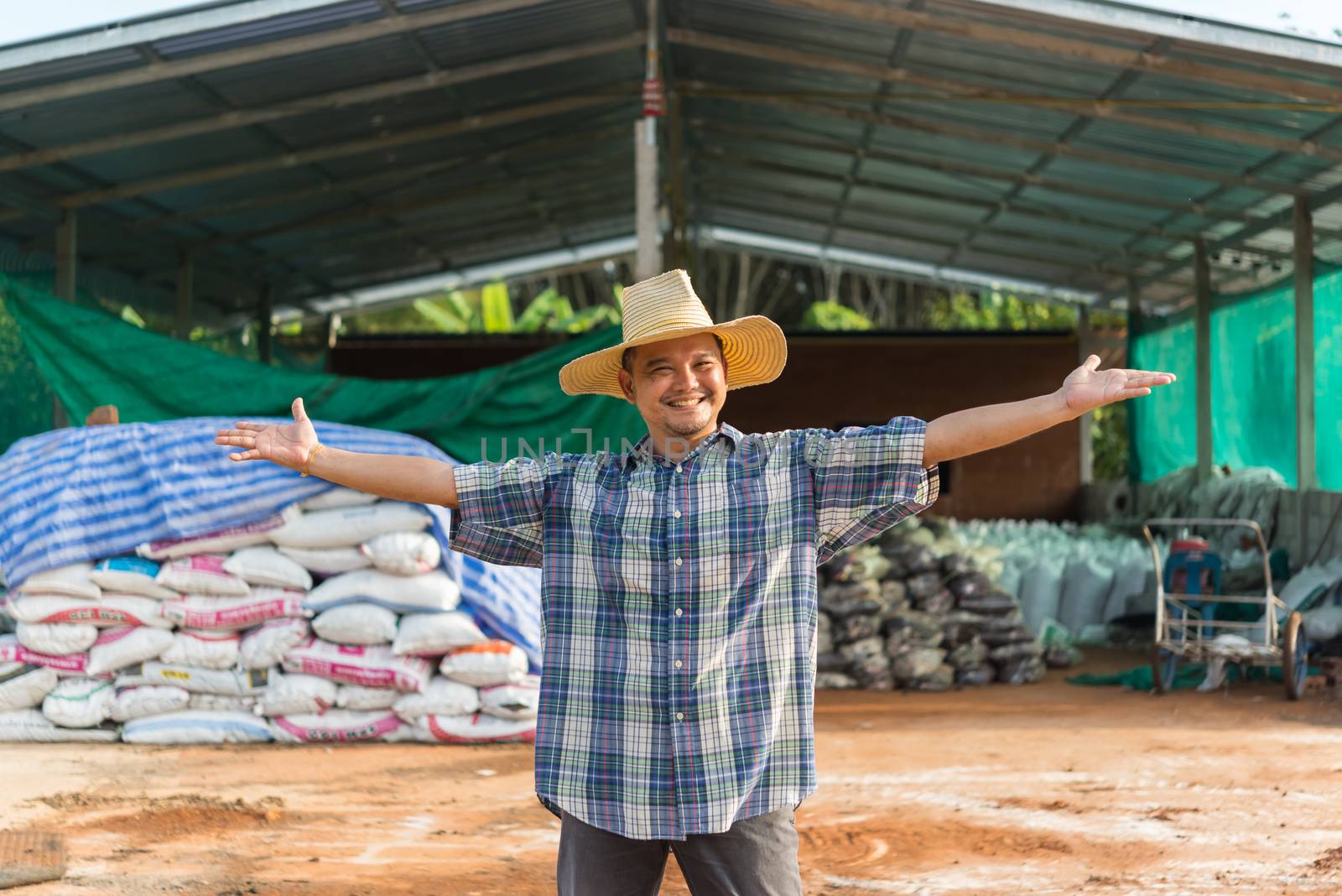 Asian man farmer agriculturist happy at a Fertilizer composting plant with Organic Fertilizer, Compost (Aerobic Microorganisms) from animal waste for use in the organic agriculture industry