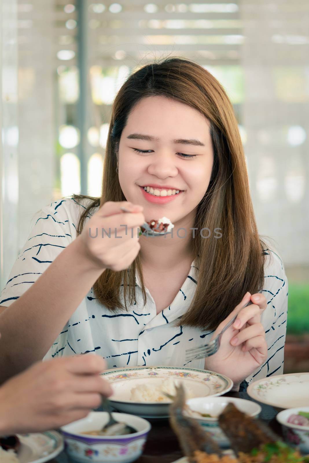Asian pretty cute woman eating thai food with rice and many food on dining table in restaurant with happy and enjoy emotion