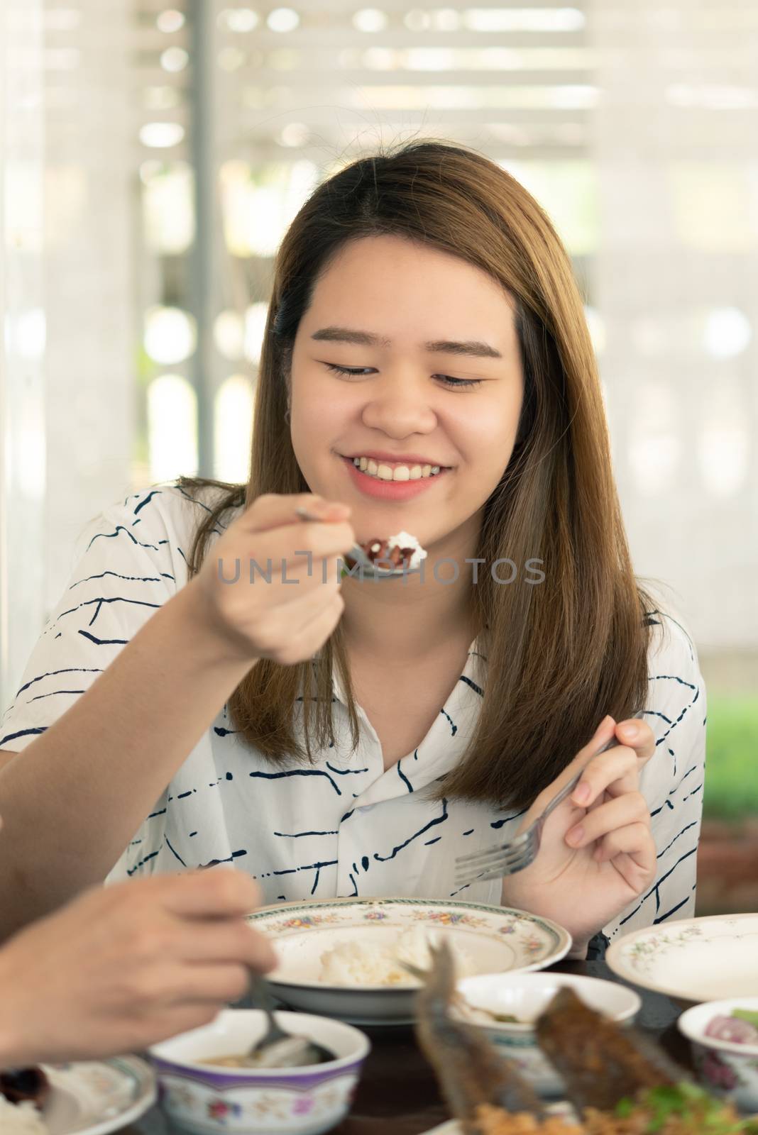 Woman eating food on dining table in restaurant by PongMoji