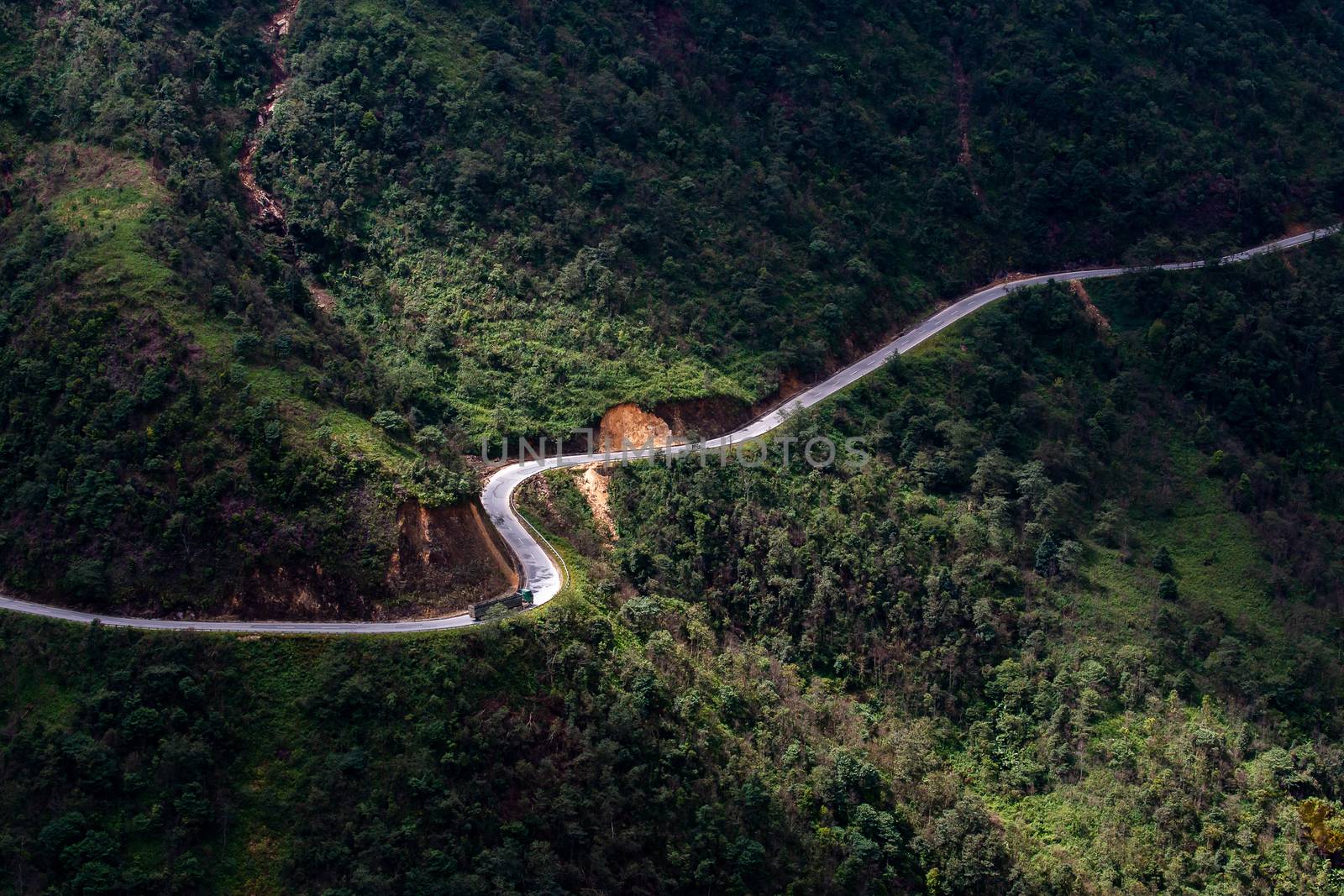 Top view ofcountryside road passing through the green forrest and mountain