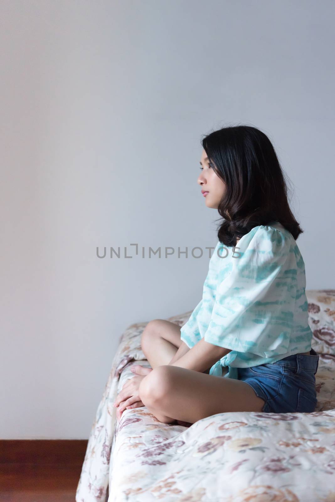 Asian pretty woman short jeans sitting on bed in bedroom alone with loneliness and lonely emotion in concept depressed feeling, depression, problem in life