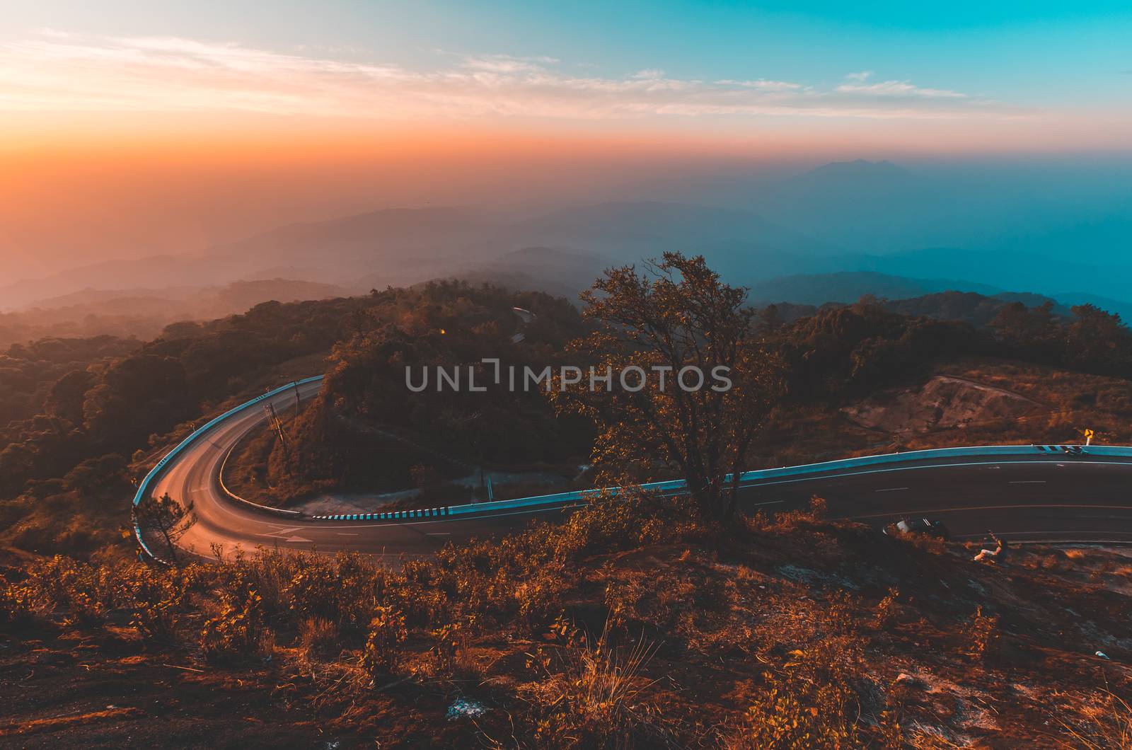 Top view of countryside road passing through the green forrest and mountain