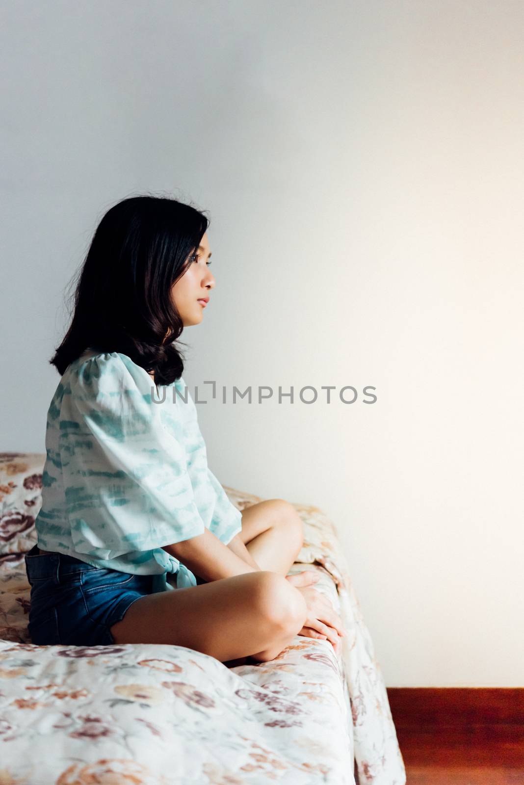 Asian pretty woman short jeans sitting on bed in bedroom alone with loneliness and lonely emotion in concept depressed feeling, depression, problem in life