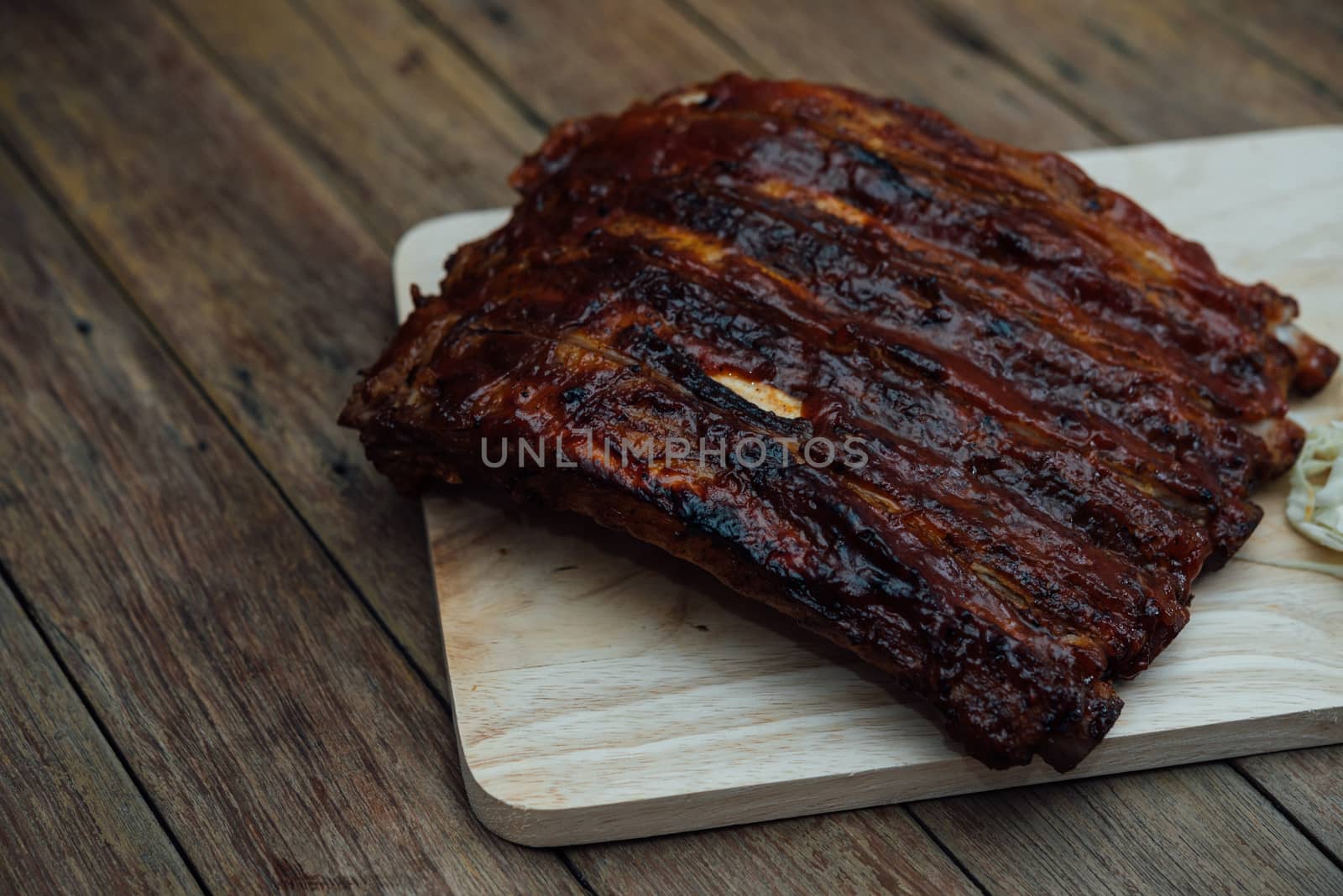 Roasted Pork Spare Ribs Barbecue or Pork Ribs with BBQ Sauce on wooden cutting board in kitchen at Thai street food market or restaurant