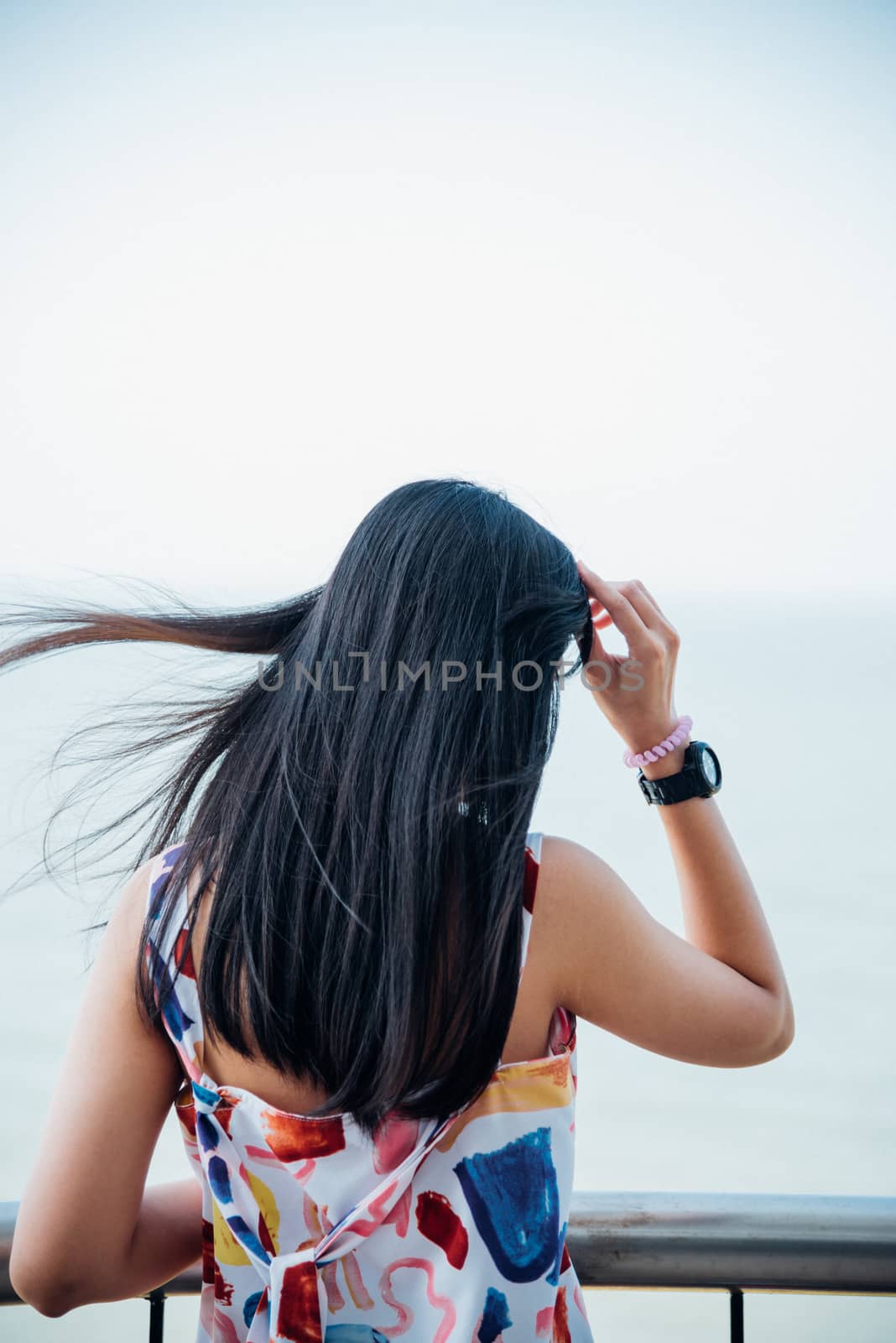 Asian pretty woman with hair blown relax at sea viewpoint with loneliness and lonely emotion in concept travel, vacation, leisure in life