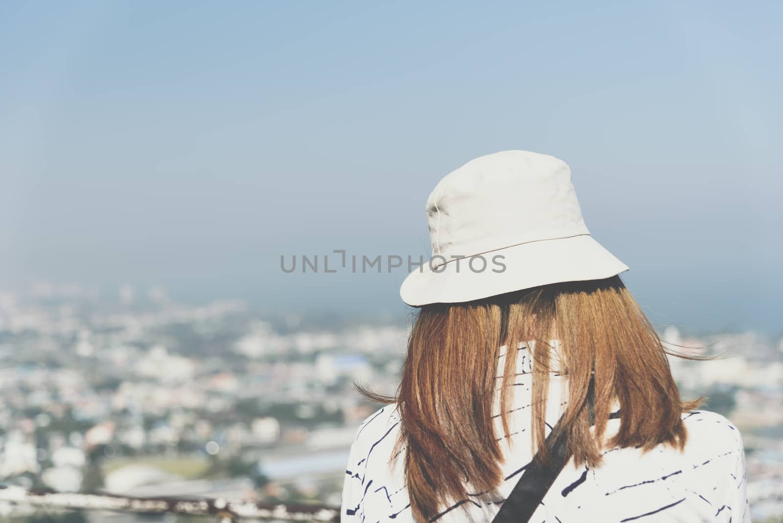 Asian pretty cute woman with hat relax at seaside city landscape viewpoint on mountain with happy and freedom emotion in concept travel, vacation, leisure in life