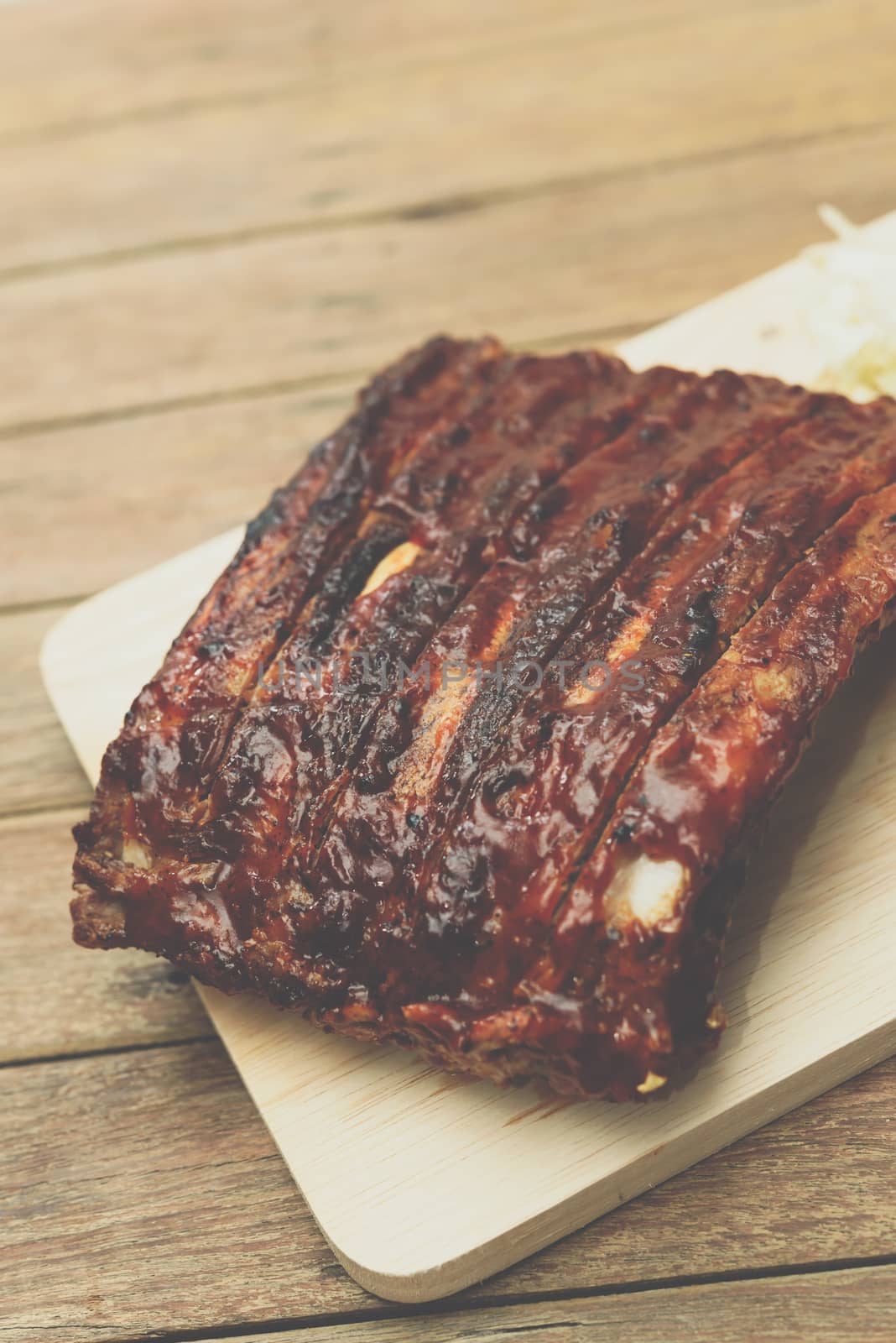 Roasted Pork Spare Ribs Barbecue or Pork Ribs with BBQ Sauce on wooden cutting board in kitchen at Thai street food market or restaurant