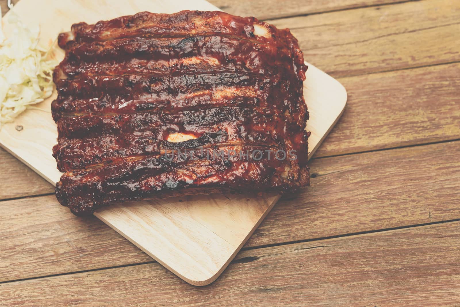 Roasted Pork Spare Ribs Barbecue or Pork Ribs with BBQ Sauce on wooden cutting board in kitchen at Thai street food market or restaurant