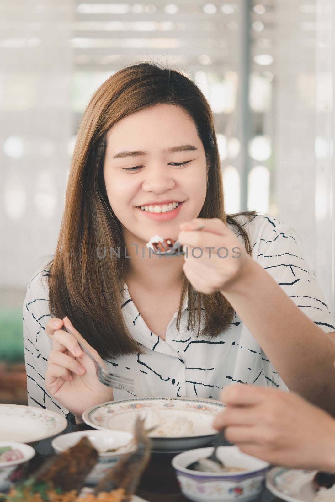 Asian pretty cute woman eating thai food with rice and many food on dining table in restaurant with happy and enjoy emotion