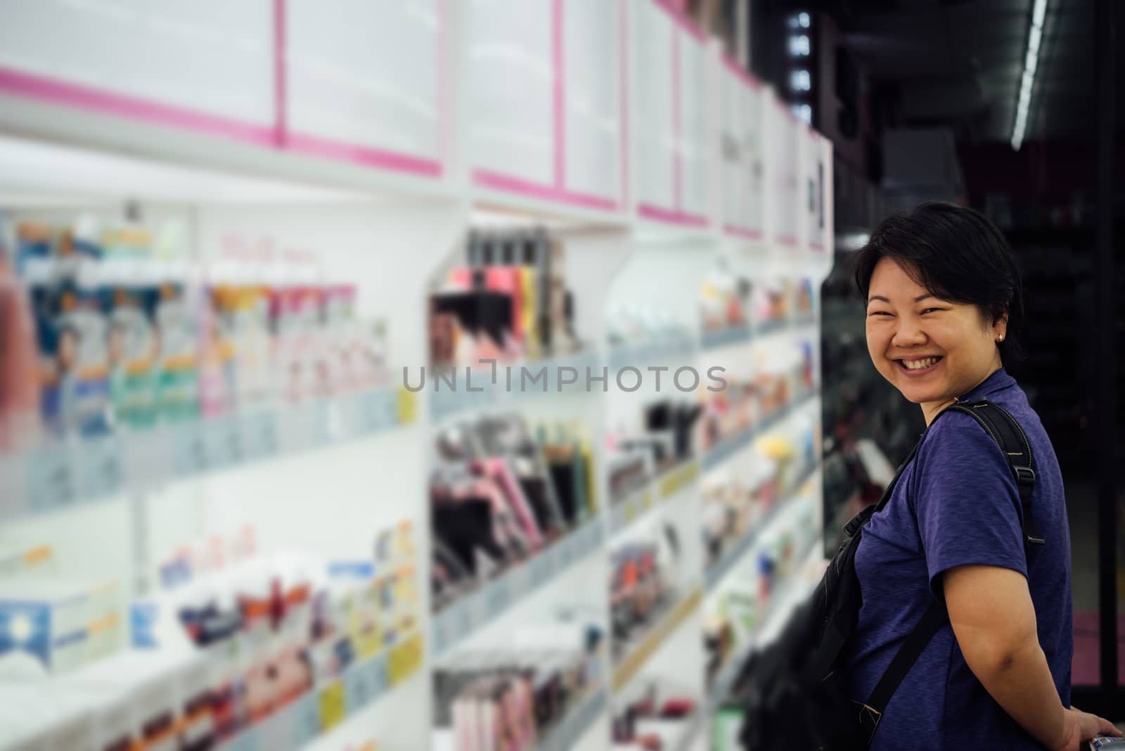 Asian woman with many types of cosmetics for beauty and skin health products for sale in supermarket open daily