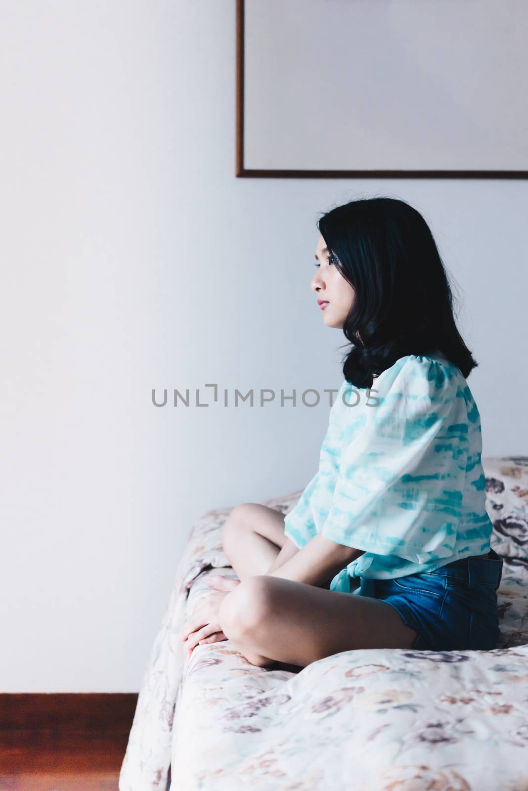 Asian pretty woman short jeans sitting on bed in bedroom alone with loneliness and lonely emotion in concept depressed feeling, depression, problem in life