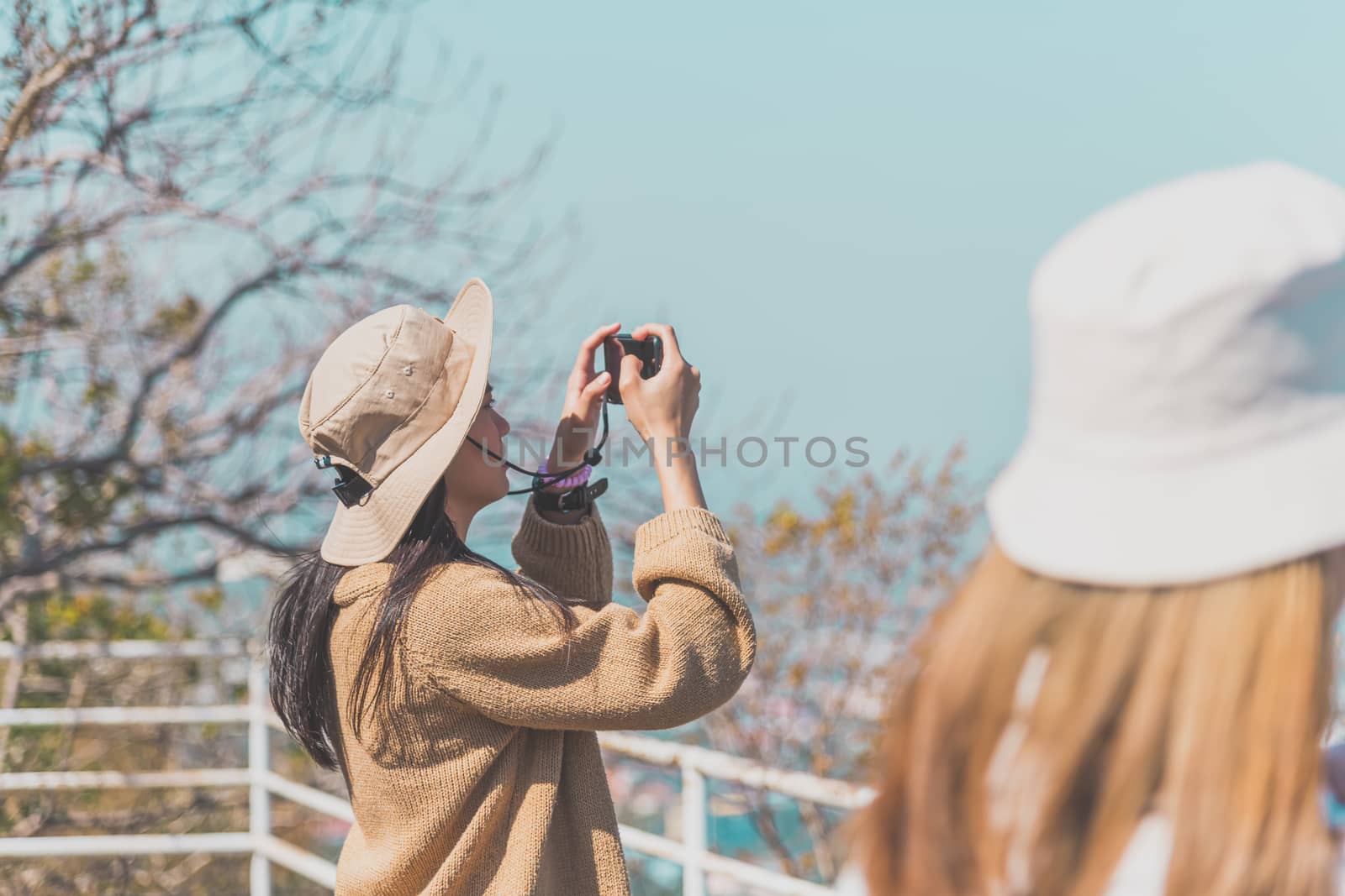 Asian pretty cute woman with hat relax and use smartphone at seaside city landscape viewpoint on mountain with happy and freedom emotion in concept travel, vacation, leisure in life