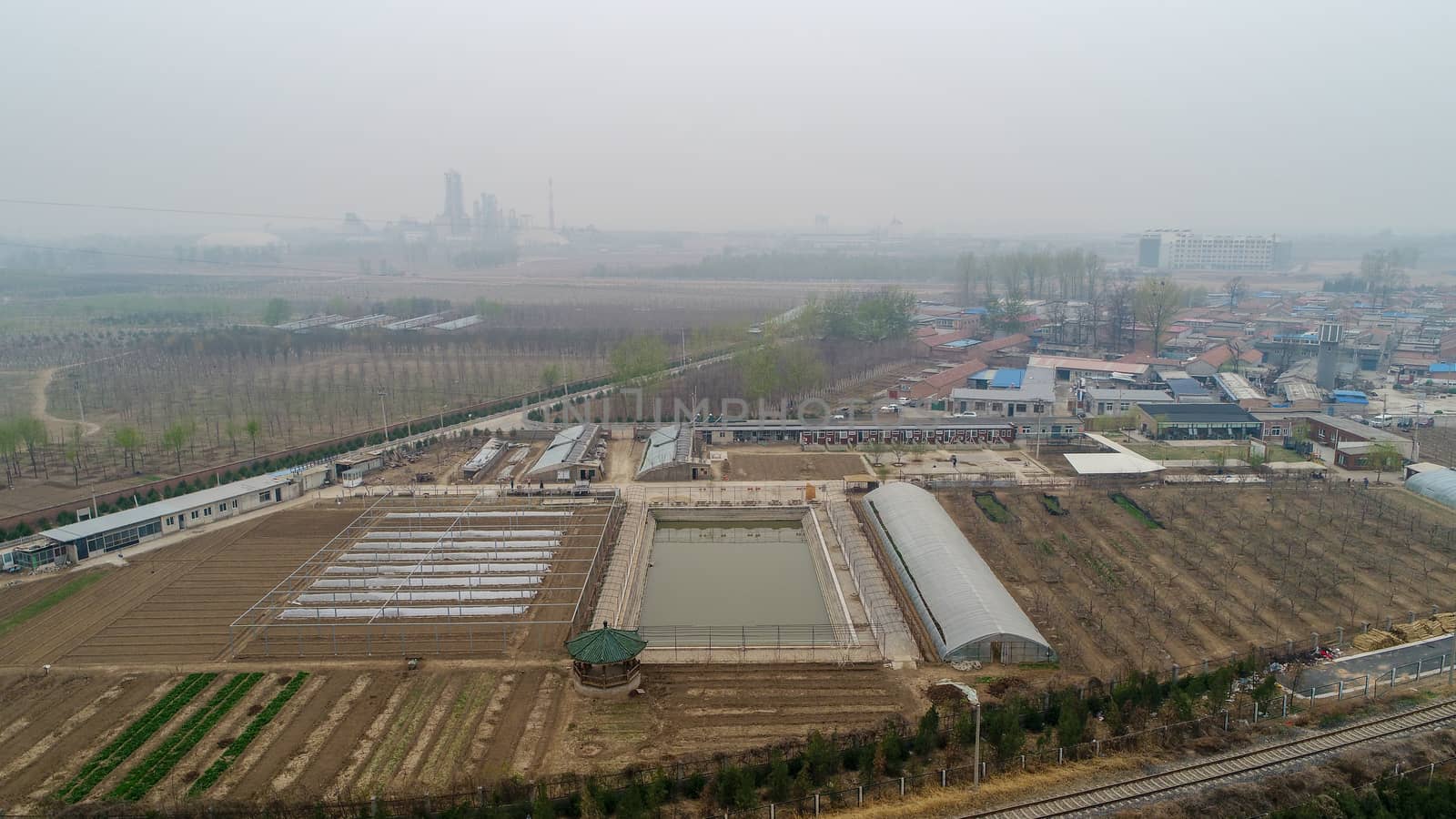 Small rural poor villages, surrounded by farm land, small factories and train tracks outside Beijing during extreme pollution gray day. China.