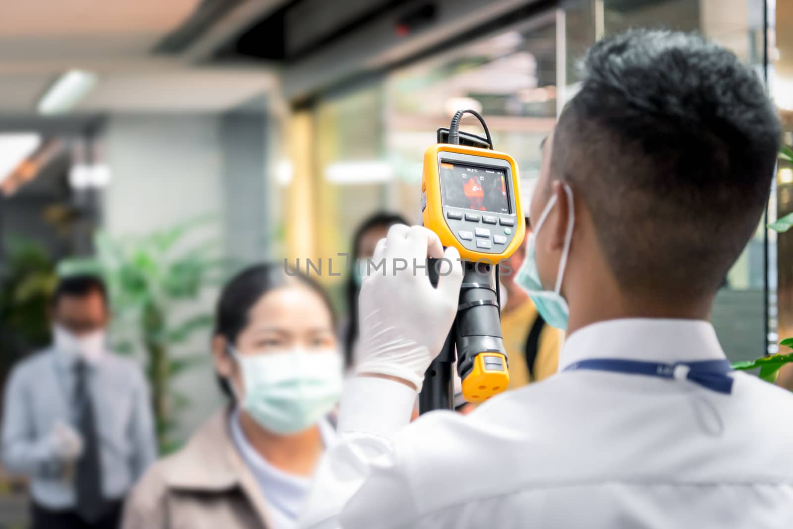 Asian people waiting for body temperature check before access to building for against epidemic flu covid19 or corona virus from wuhan in office by thermoscan or infrared thermal camera