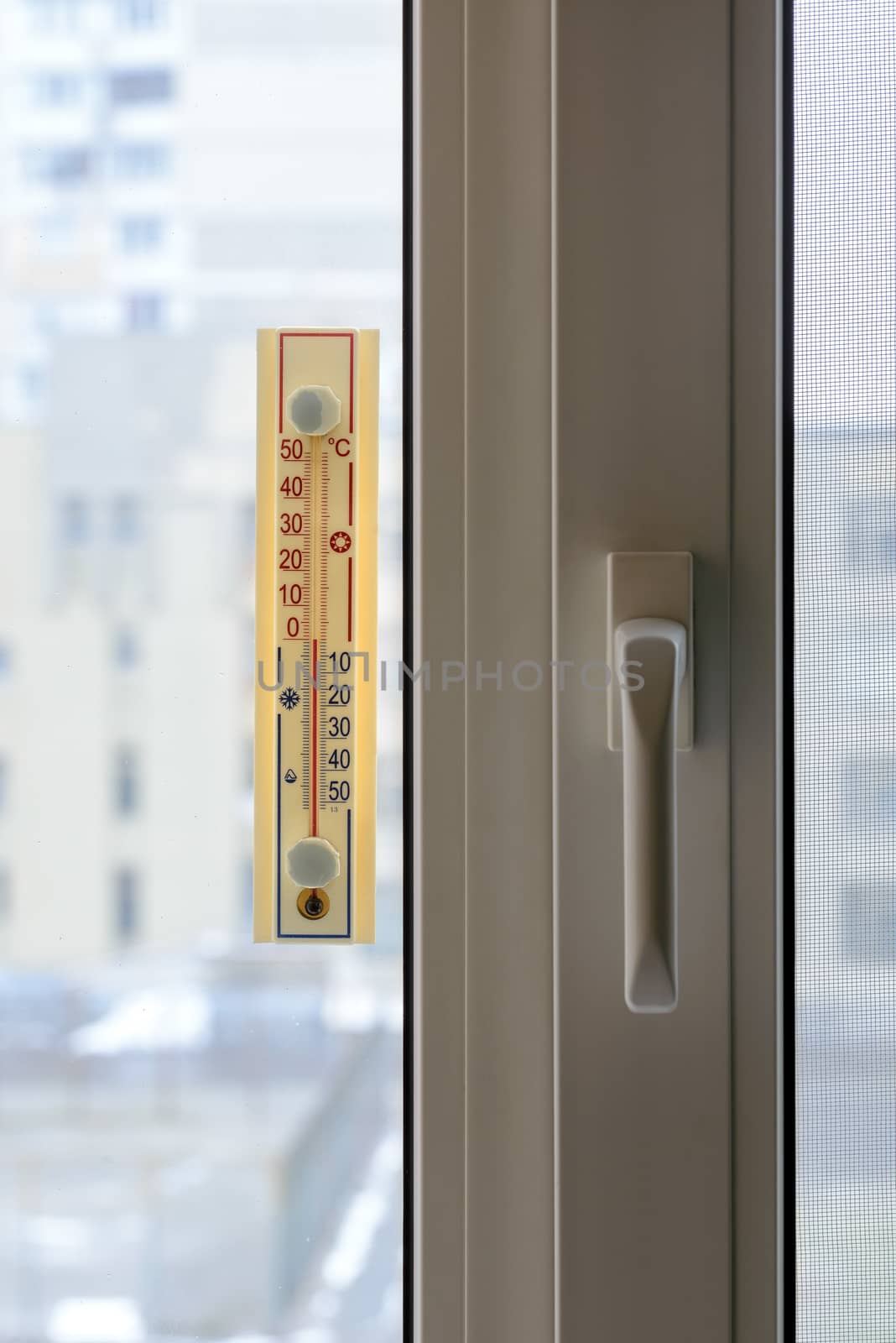 A thermometer, fixed out of the window, shows that it is zero degree celsius outdoor, while it is warm inside the room