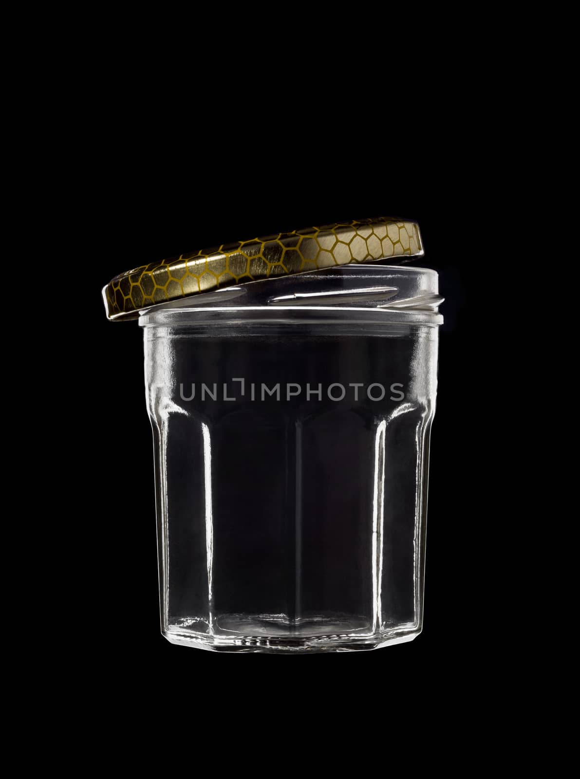 Transparent glass jar on black background, with the open gold color top