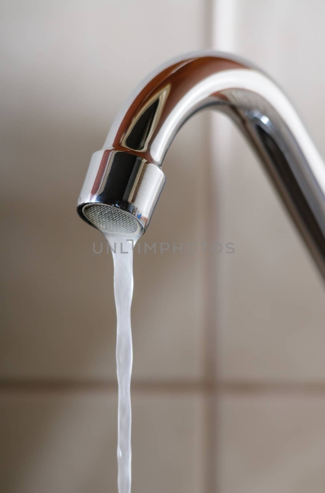 Vertical image of a tap with water flowing slowly during a period of scarcity