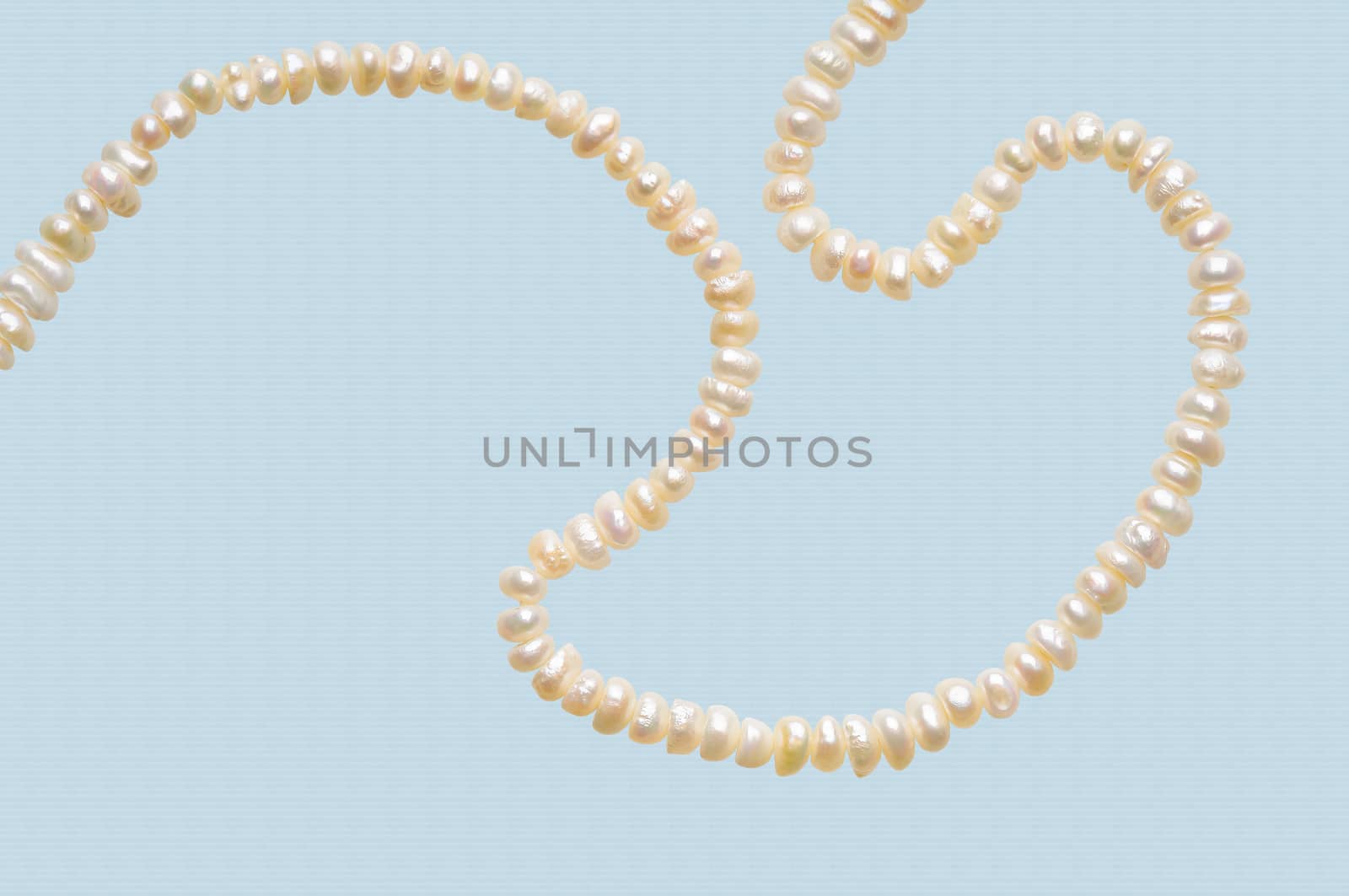 Natural pearls necklace on a sky blue stripped background