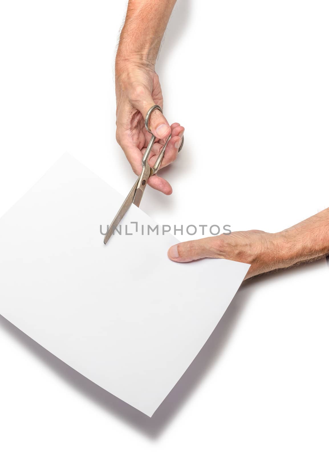 A man is cutting a sheet of white paper using  metallic scissors, on white background