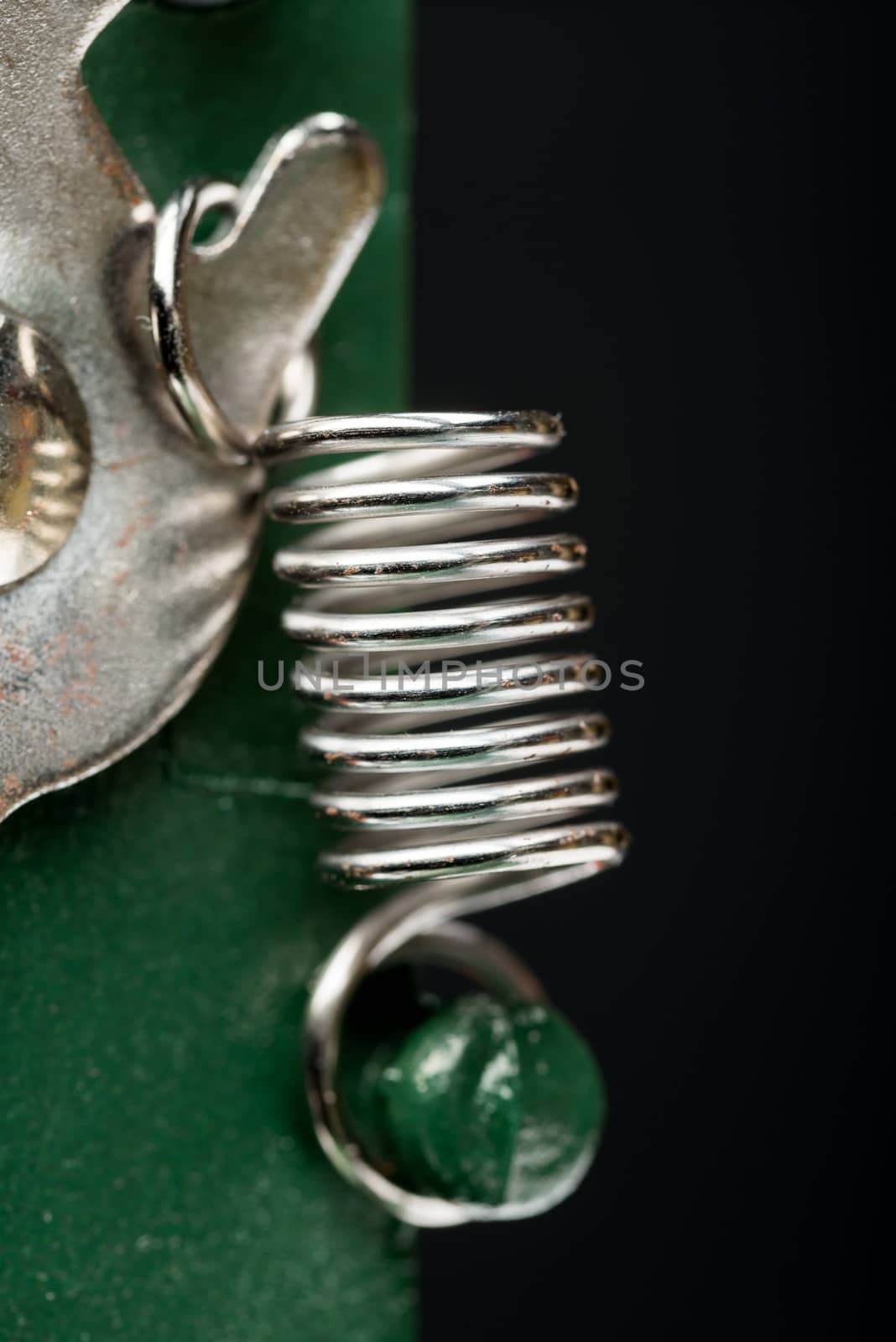 Macro detail of a metallic spring on a cutting machine, on black background