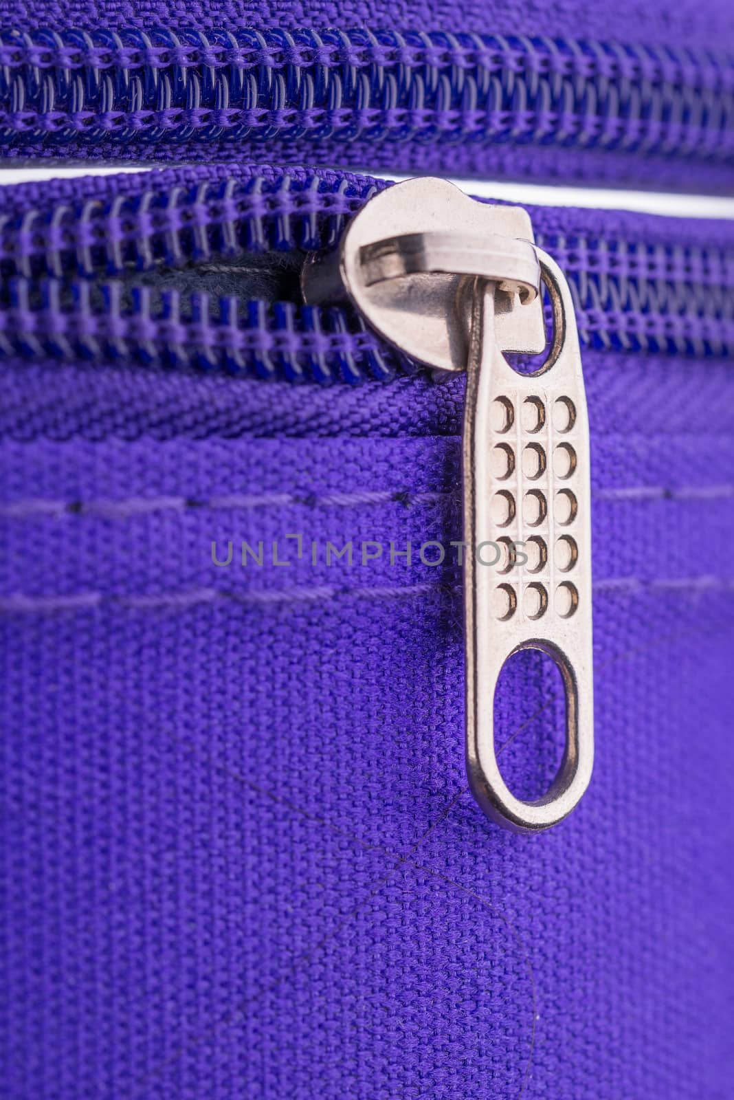 Macro of a zipper showing the pull tab and the chain on a violet suitcase ready for a safe holiday travel