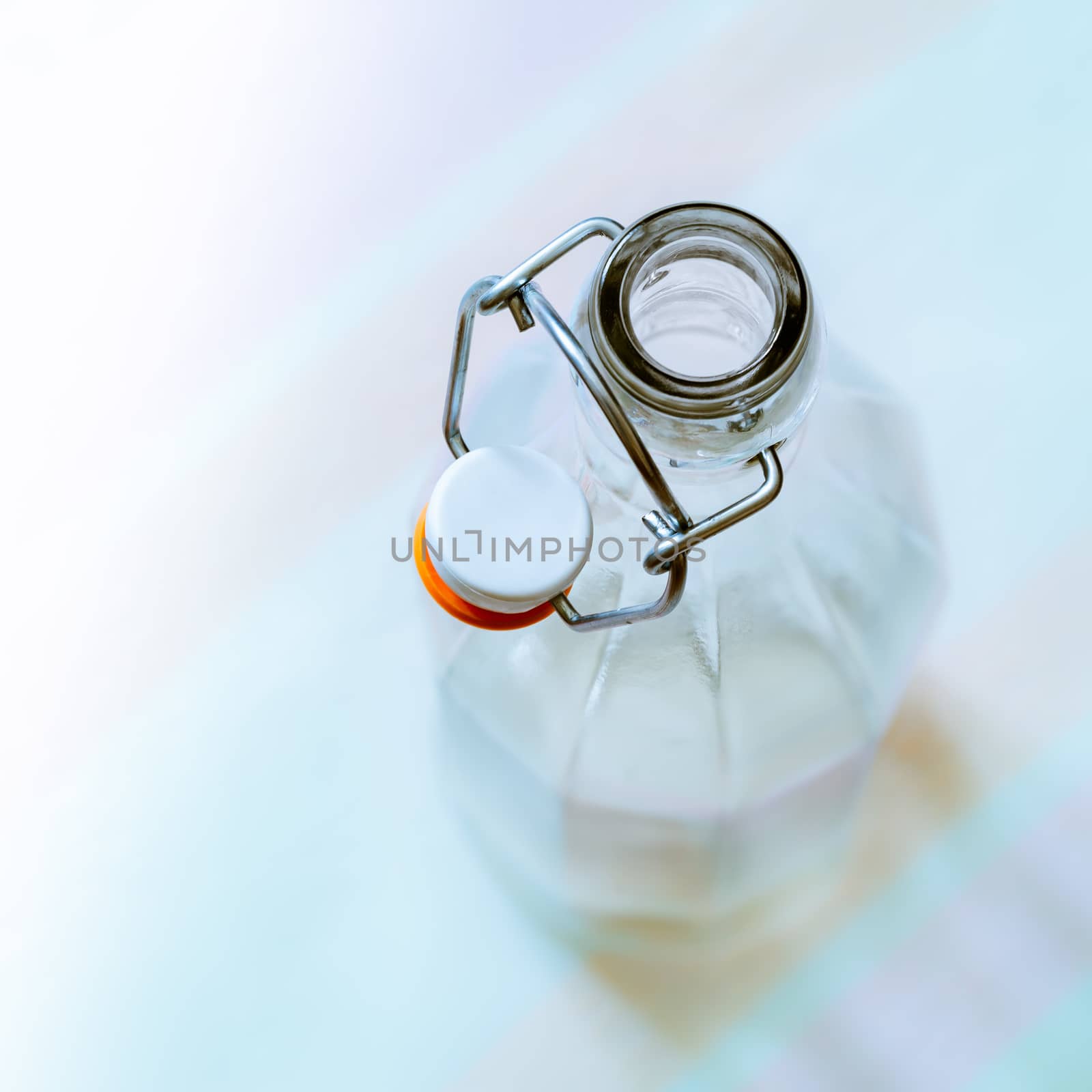 Top view of a glass bottle with a  wire bail clasp ceramic stopper on a blue, pink and orange stripped tablecloth