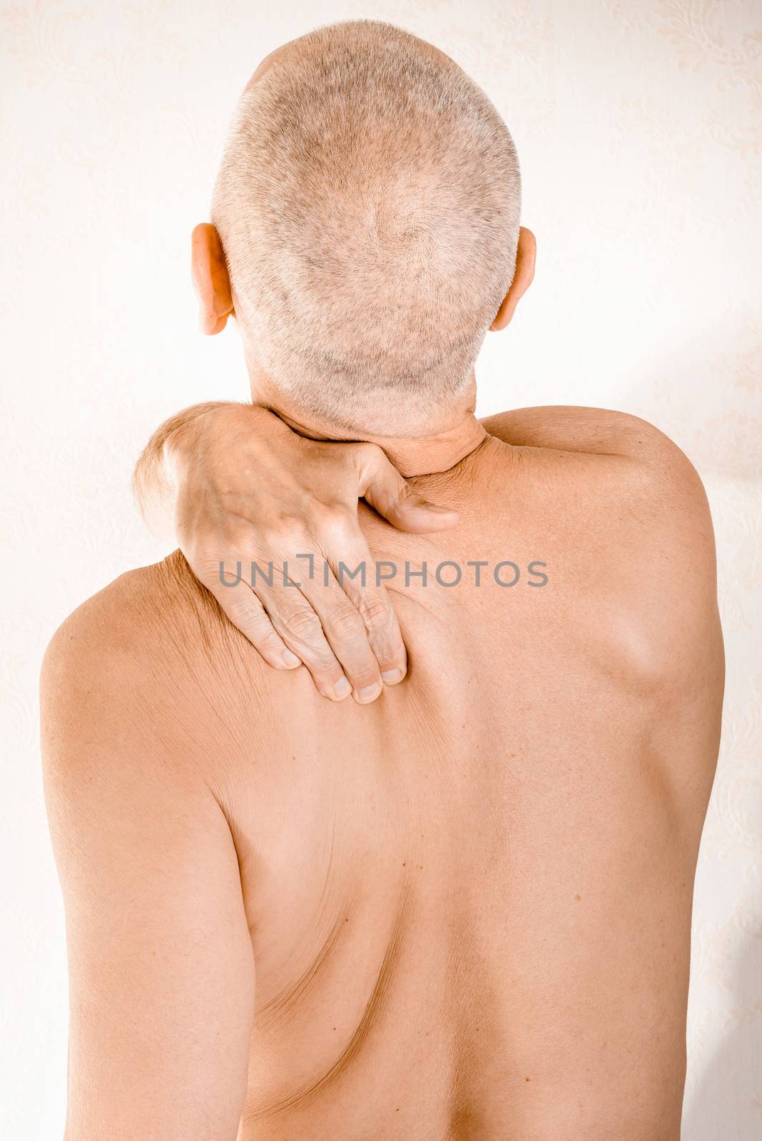 Man massaging his top back, the trapezius muscle, because of a thoracic vertebrae pain due to a displacement of a dorsal vertebra rubbing on a nerve