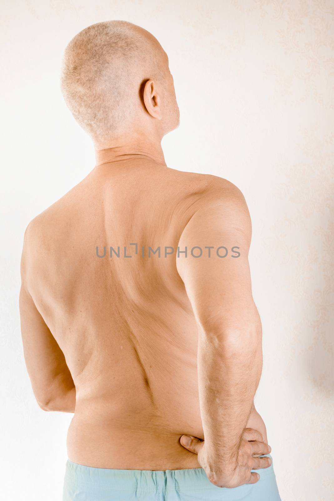 Man massaging the low back because of a painful lumbago due to a displacement of the lumbar vertebrae