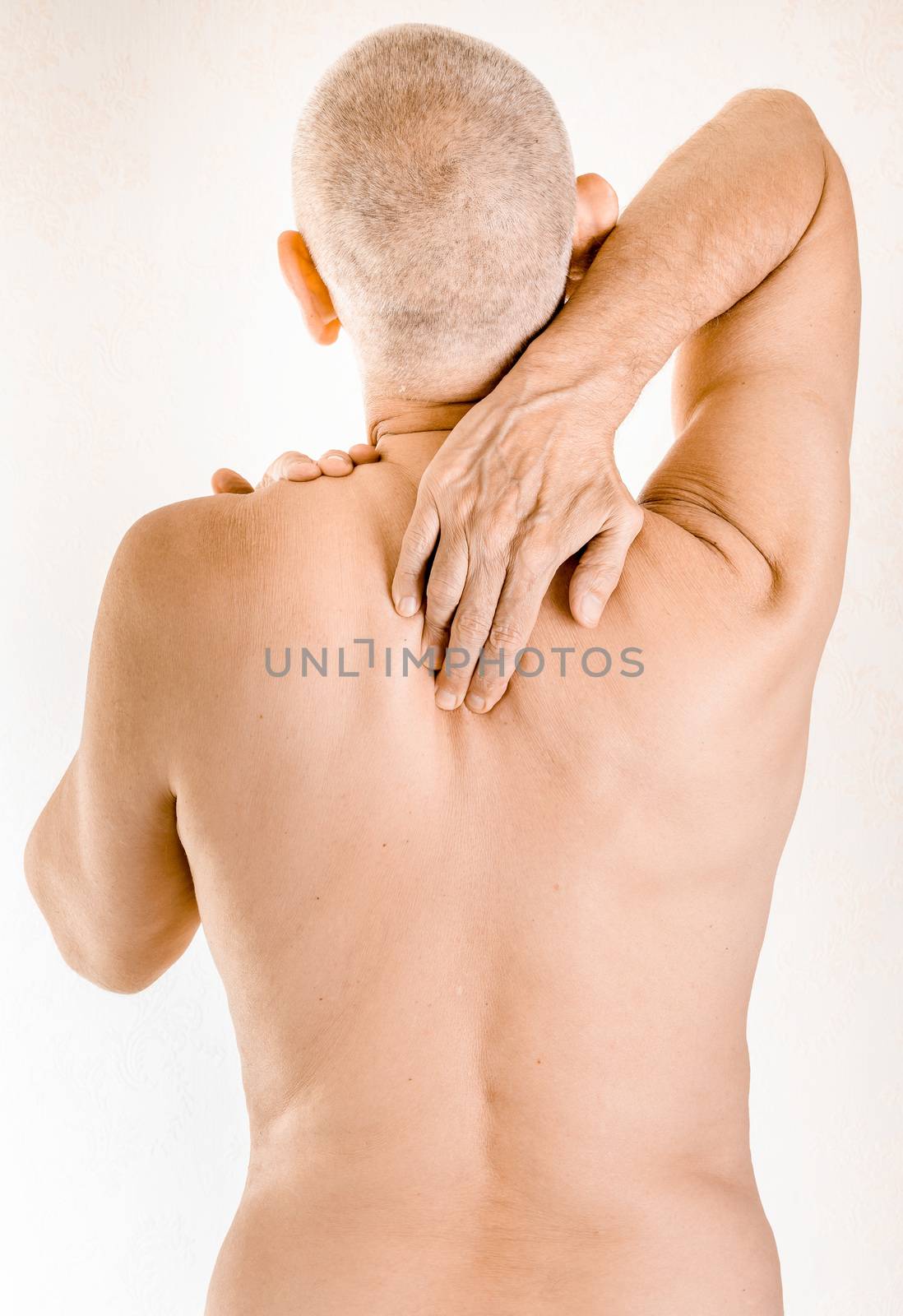 Man massaging his top back, between the shoulders, because of a thoracic vertebrae pain due to a displacement of a dorsal vertebra rubbing on a nerve