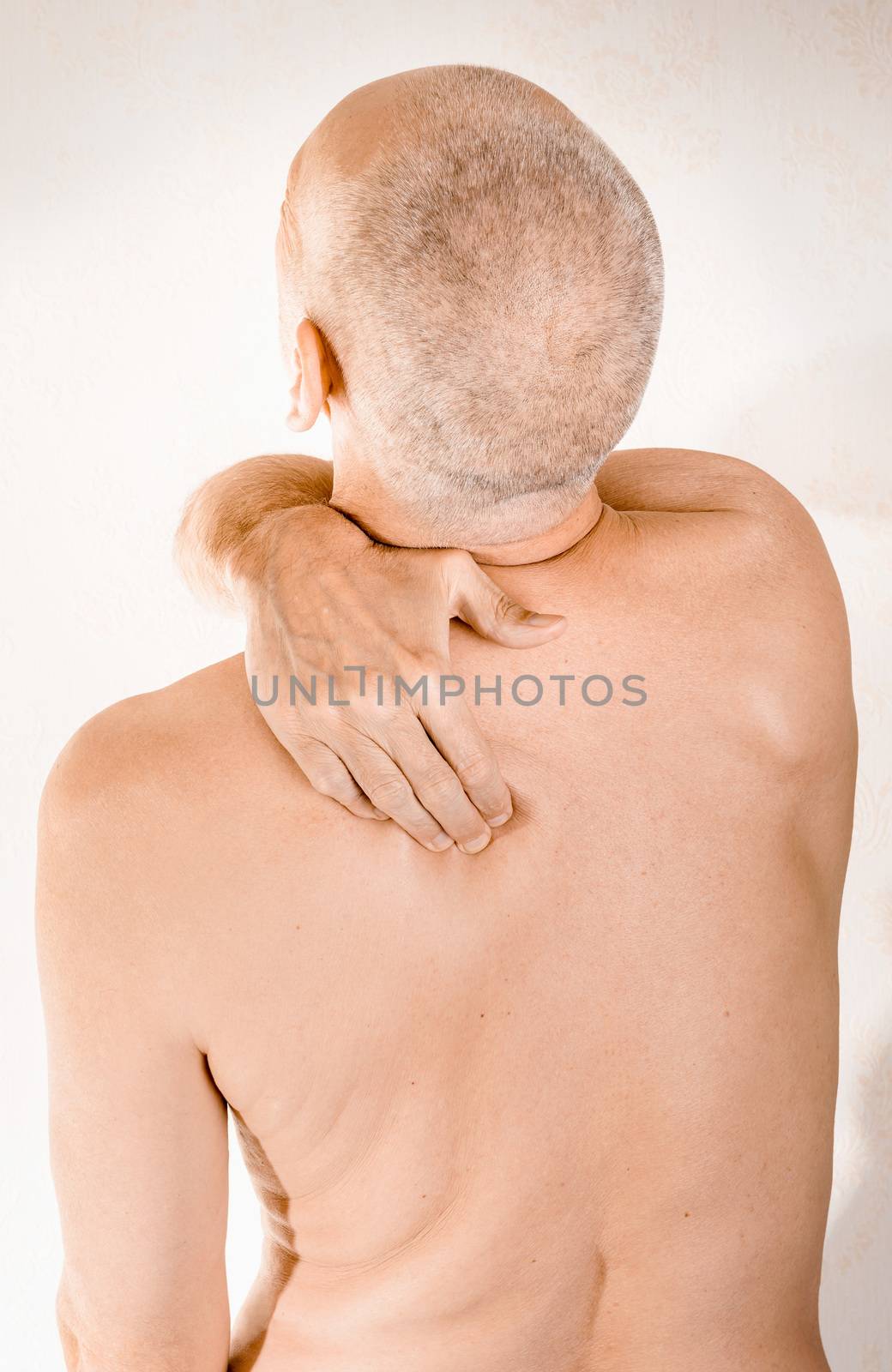 Man massaging his top back, the trapezius muscle, because of a thoracic vertebrae pain due to a displacement of a dorsal vertebra rubbing on a nerve