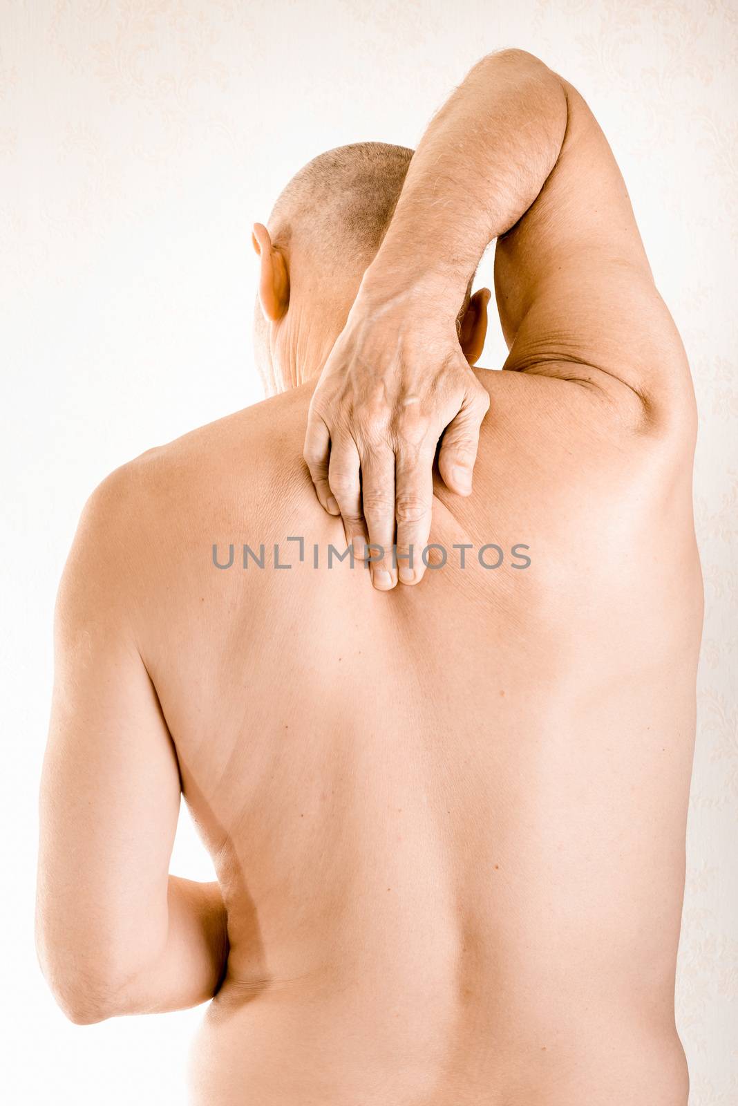 Man massaging his top back, between the shoulders, because of a thoracic vertebrae pain due to a displacement of a dorsal vertebra rubbing on a nerve