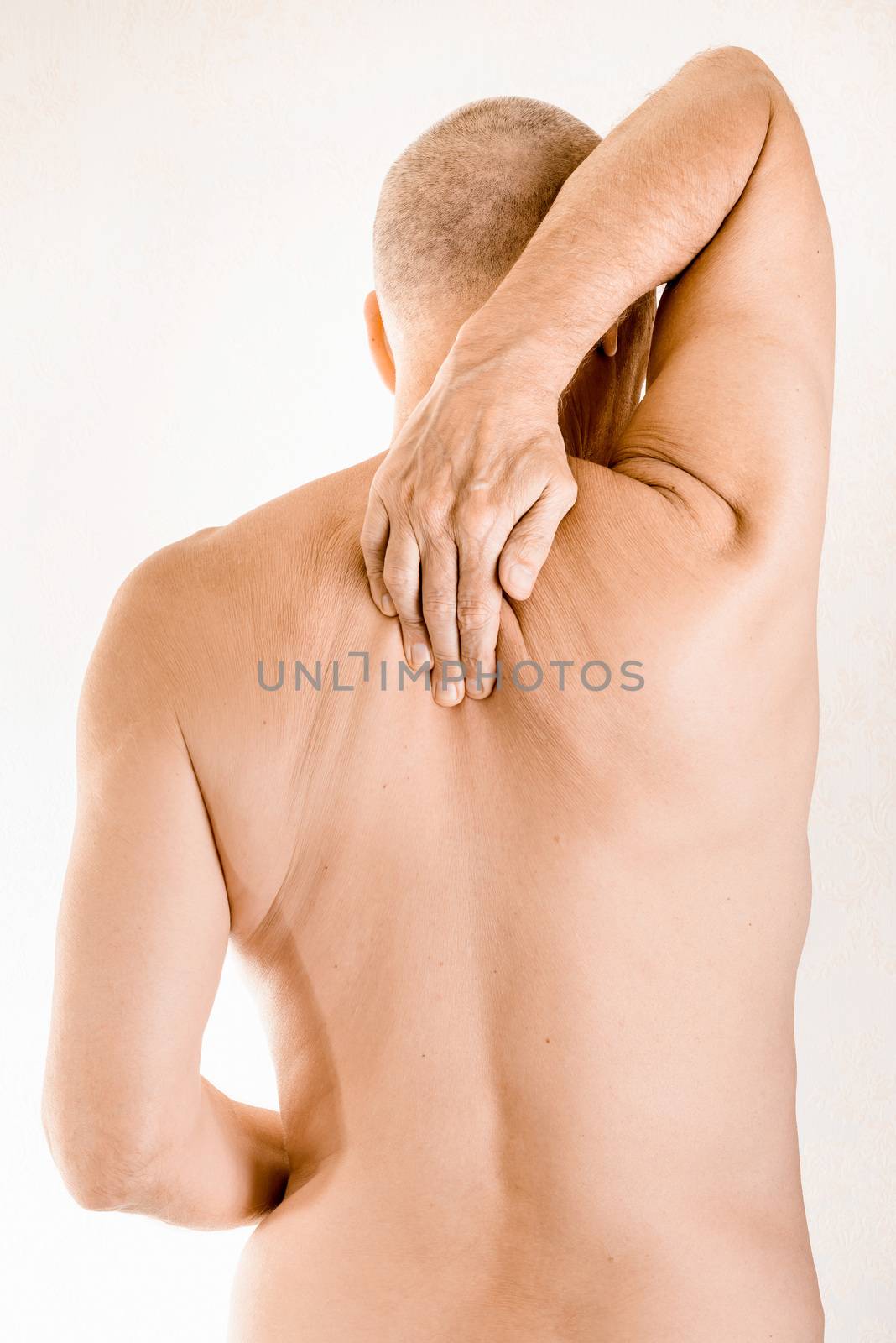 Man massaging his top back, between the shoulders, because of a thoracic vertebrae pain due to a displacement of a dorsal vertebra rubbing on a nerve