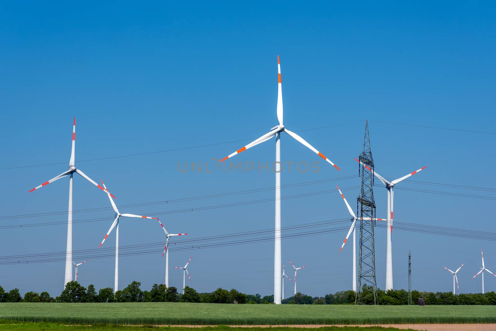 Overhead power lines and wind power plants under a blue sky in Germany